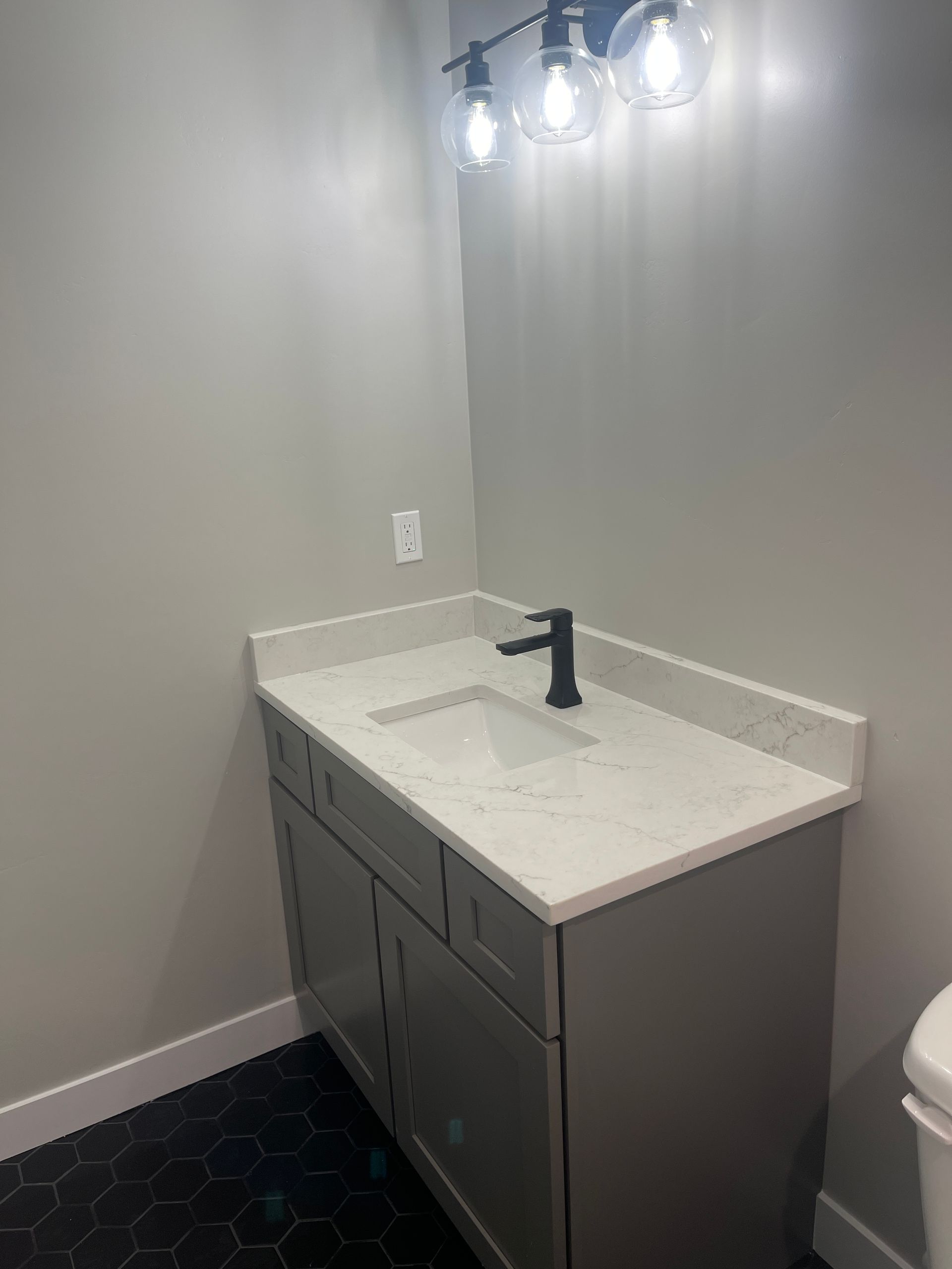 A bathroom with a sink , toilet and light fixture.
