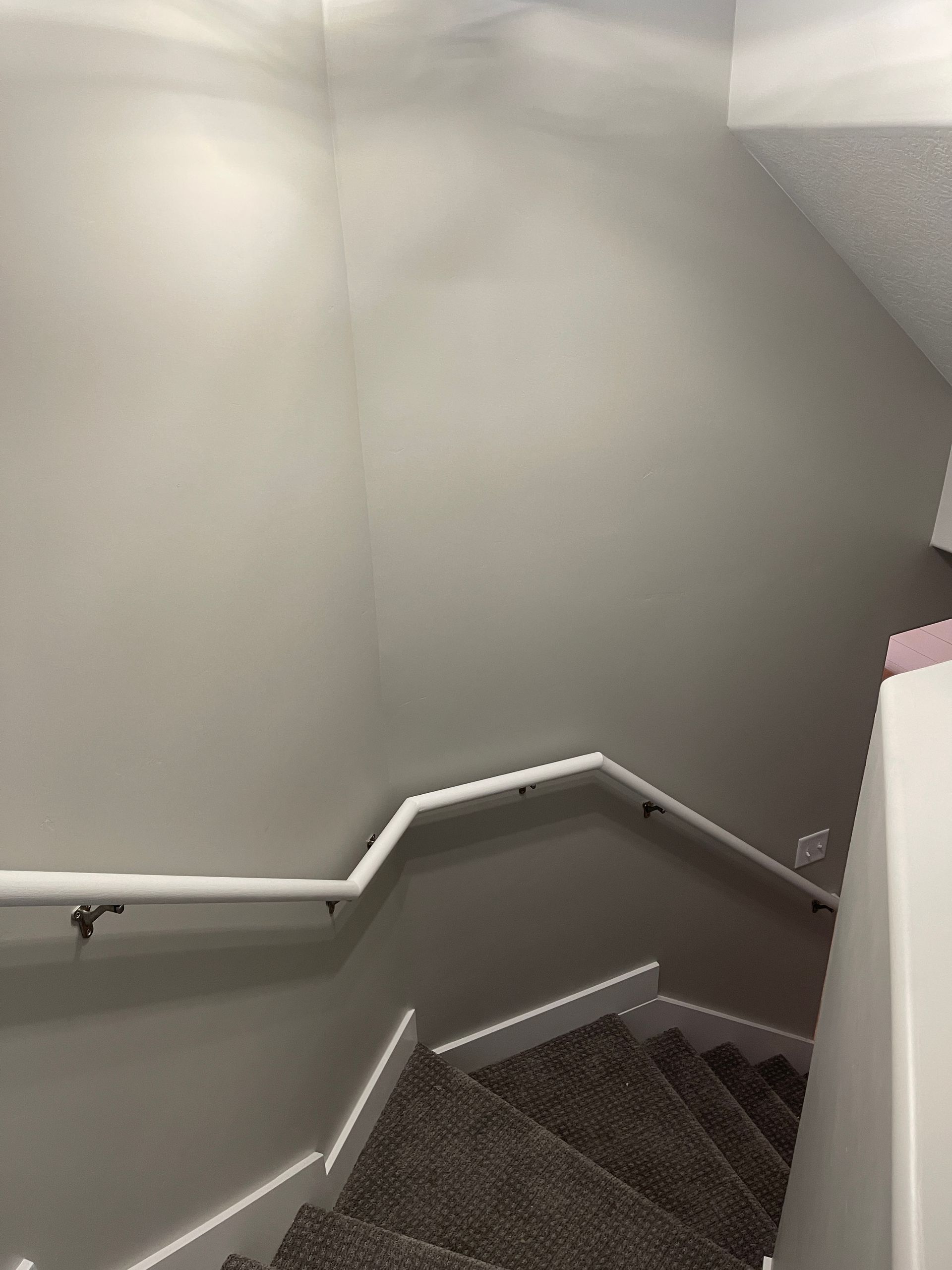 A staircase with a white railing and carpeted steps in a house.