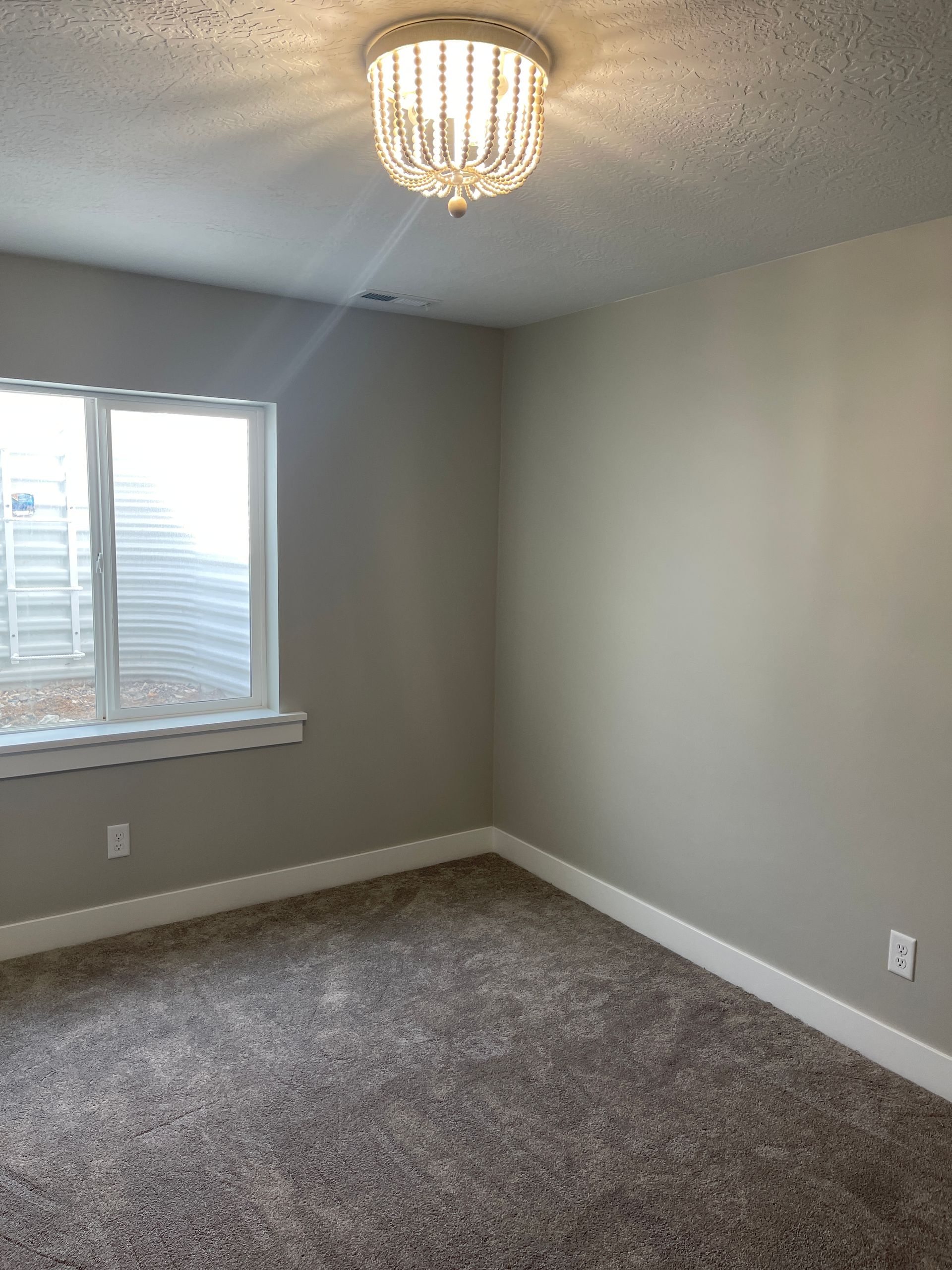 An empty bedroom with a chandelier and a window.