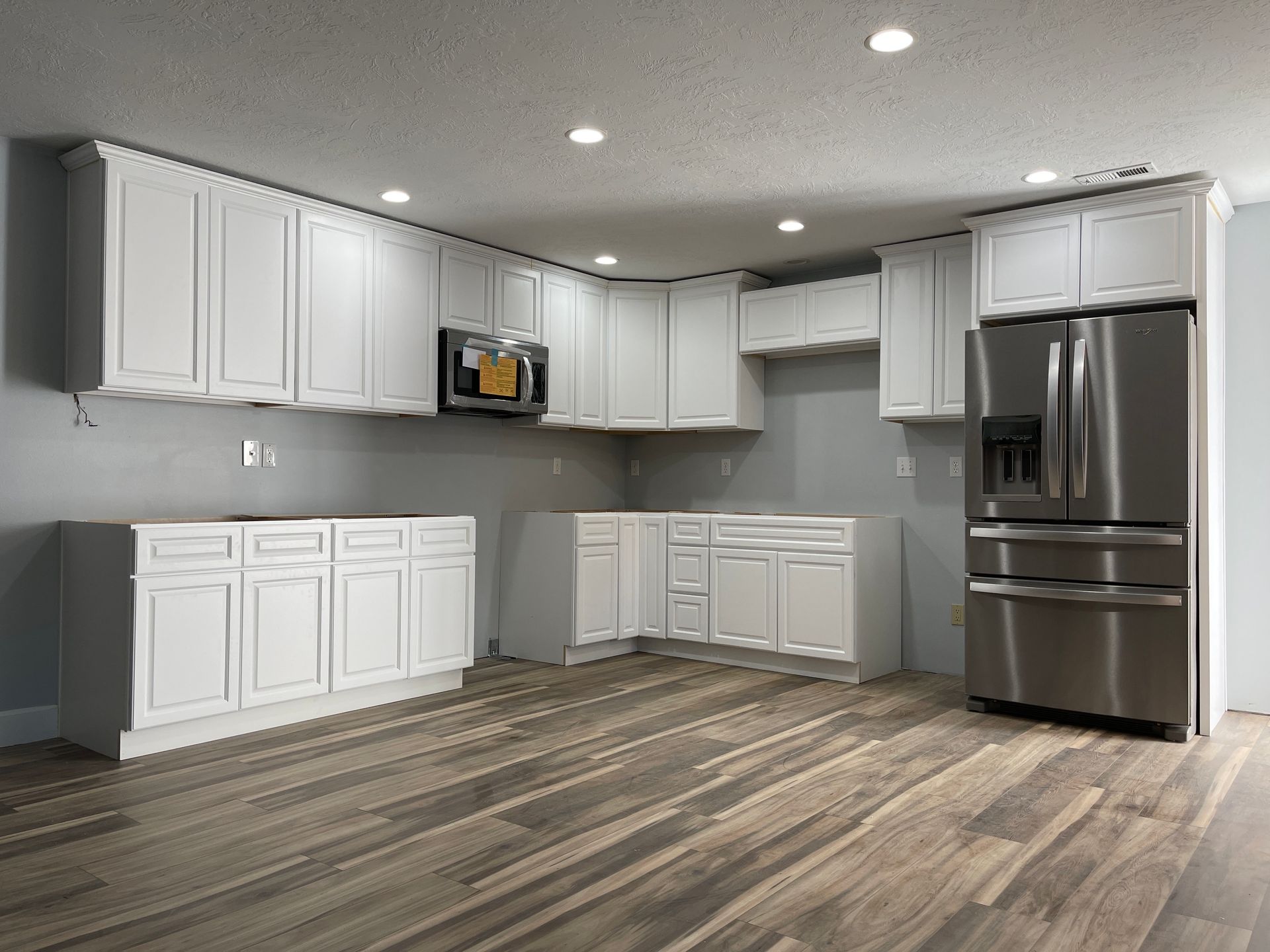An empty kitchen with white cabinets and stainless steel appliances.
