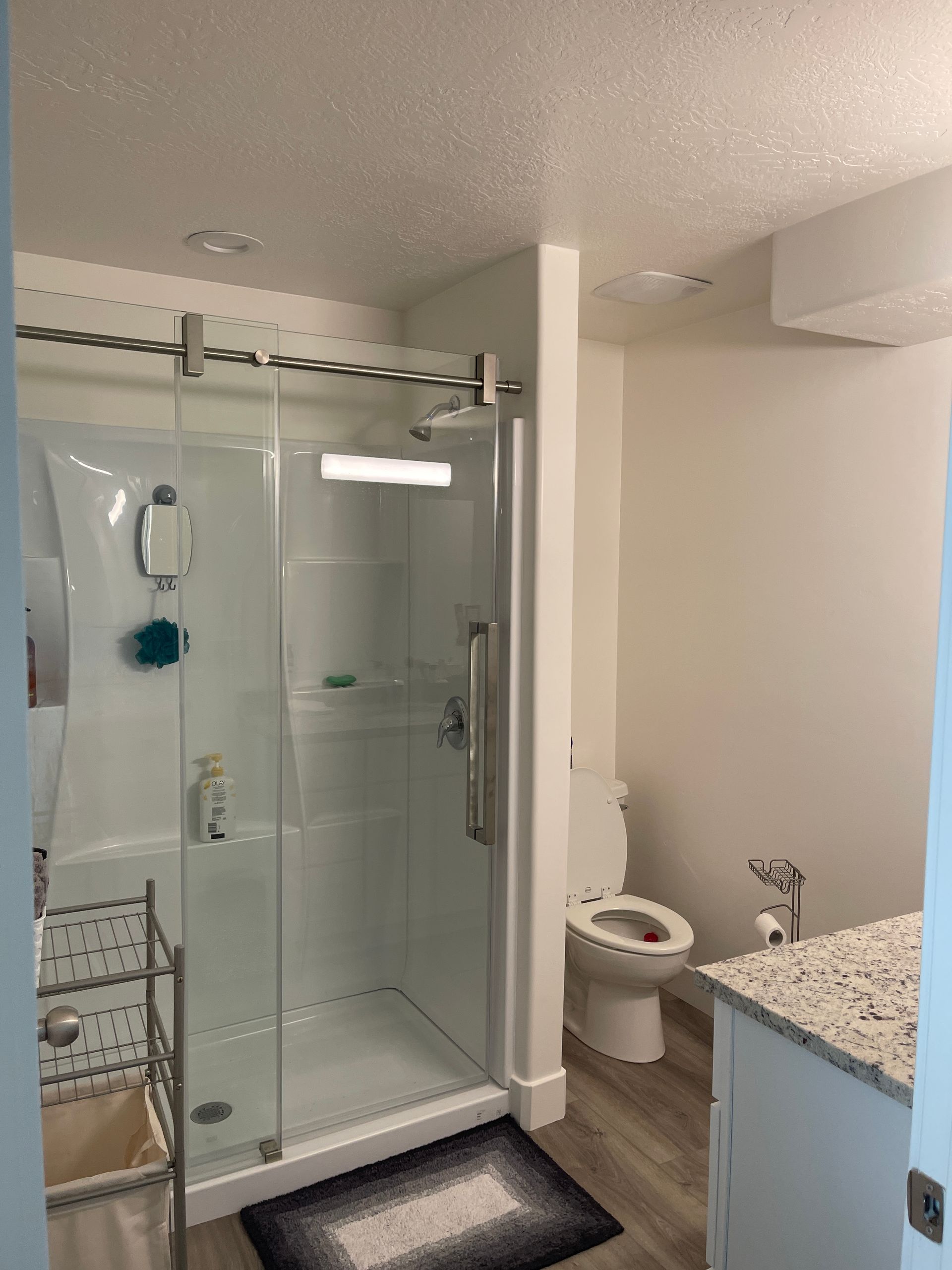 A bathroom with a toilet , sink , shower and sliding glass door.