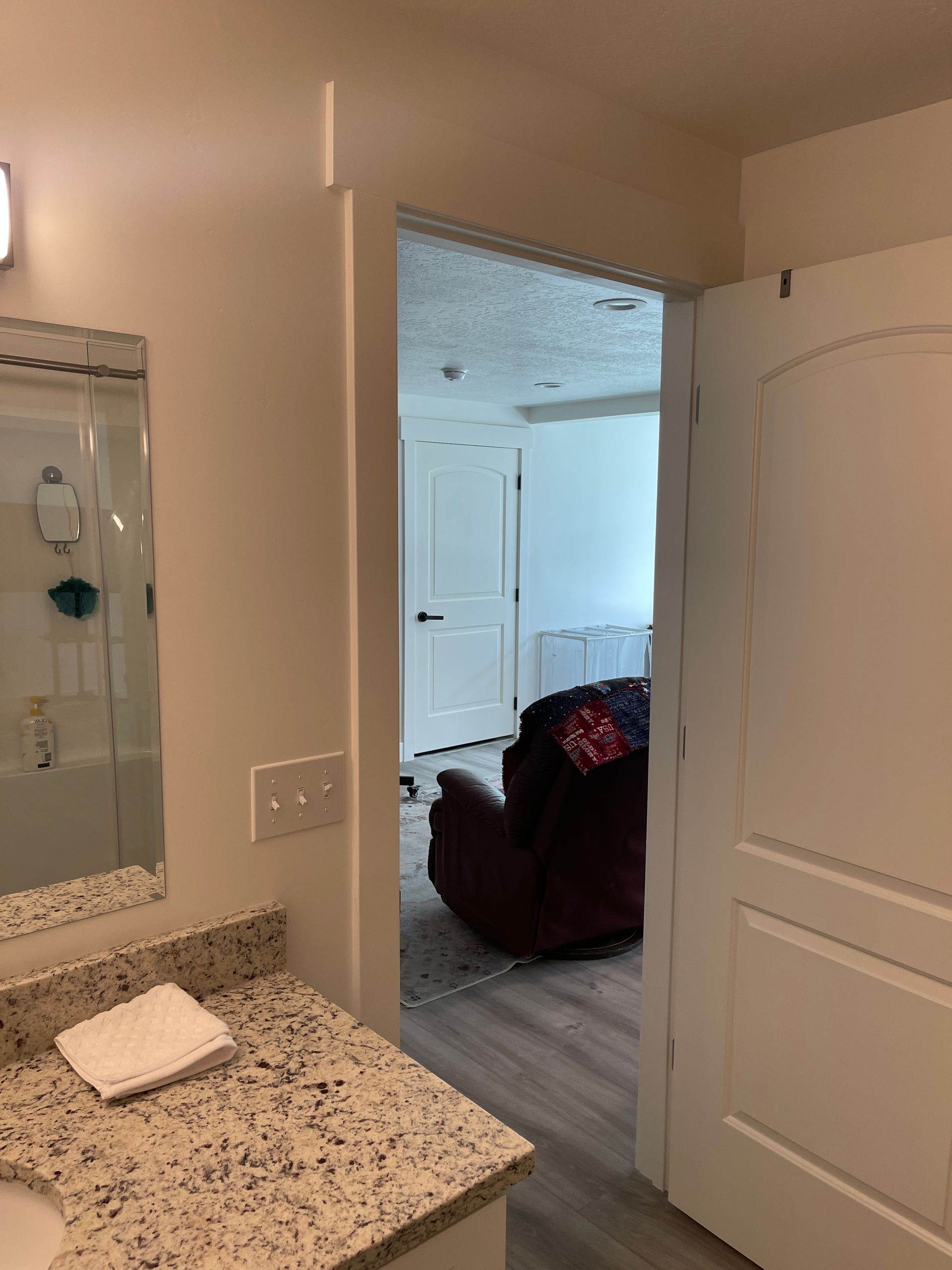 A bathroom with a sink , mirror and door leading to a living room.
