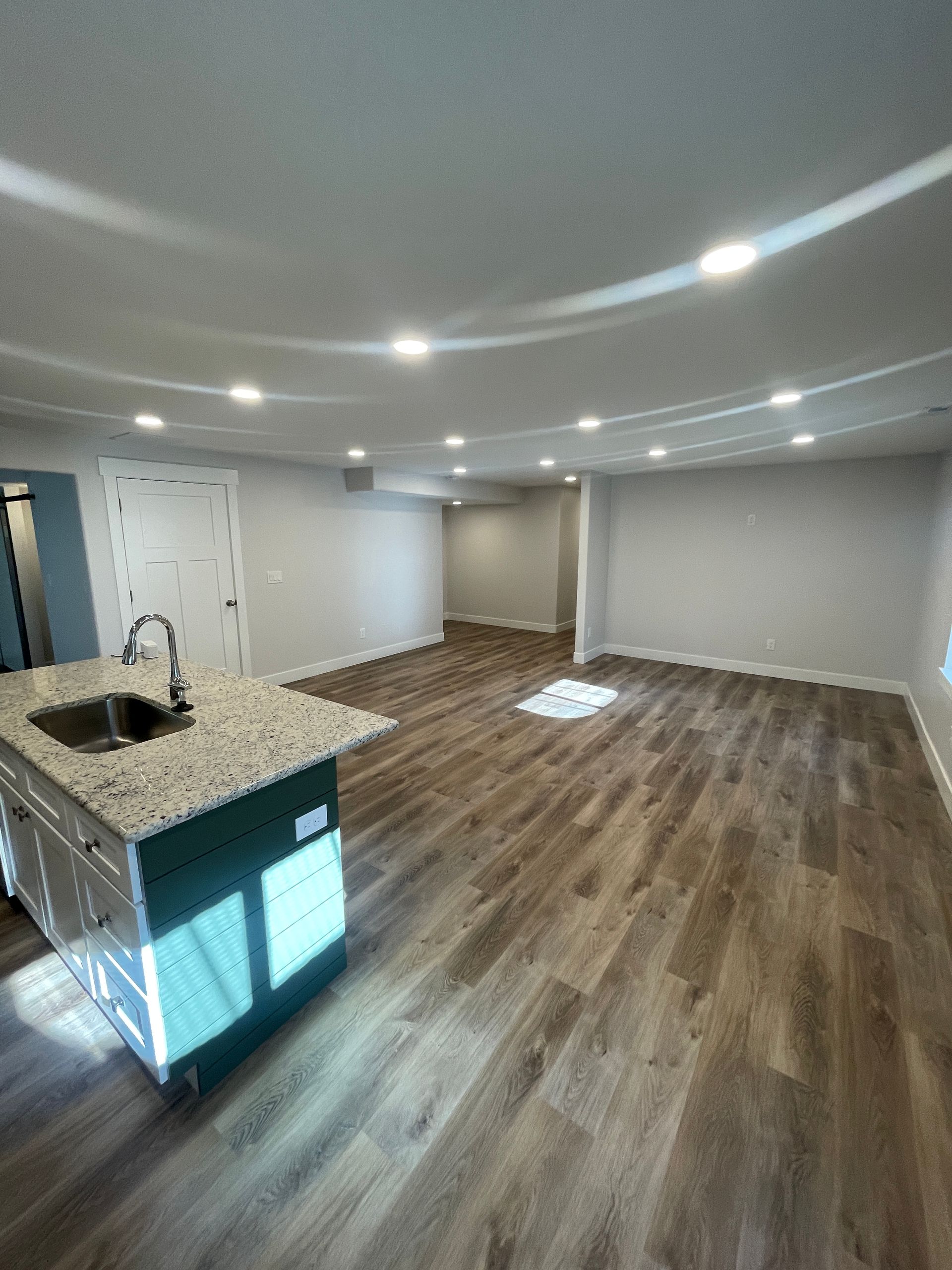 A large empty room with hardwood floors and a sink.