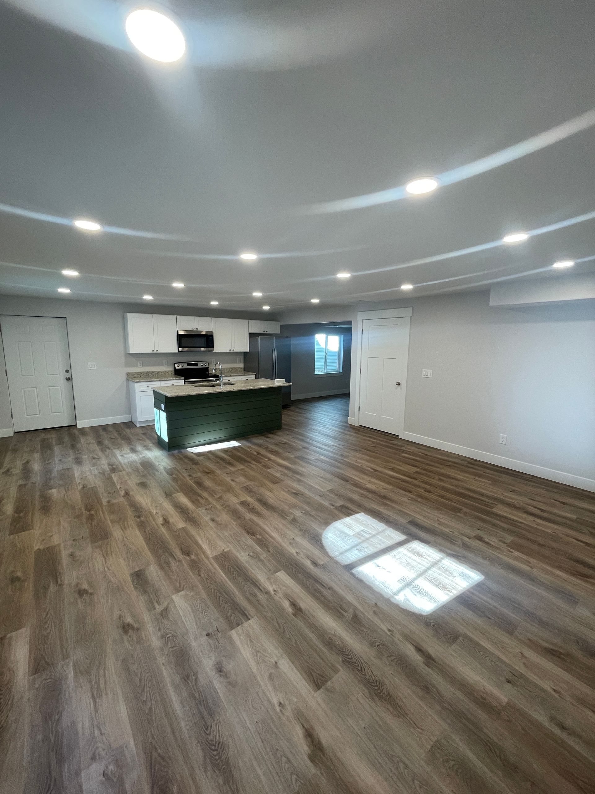 A living room with hardwood floors and a kitchen in the background.