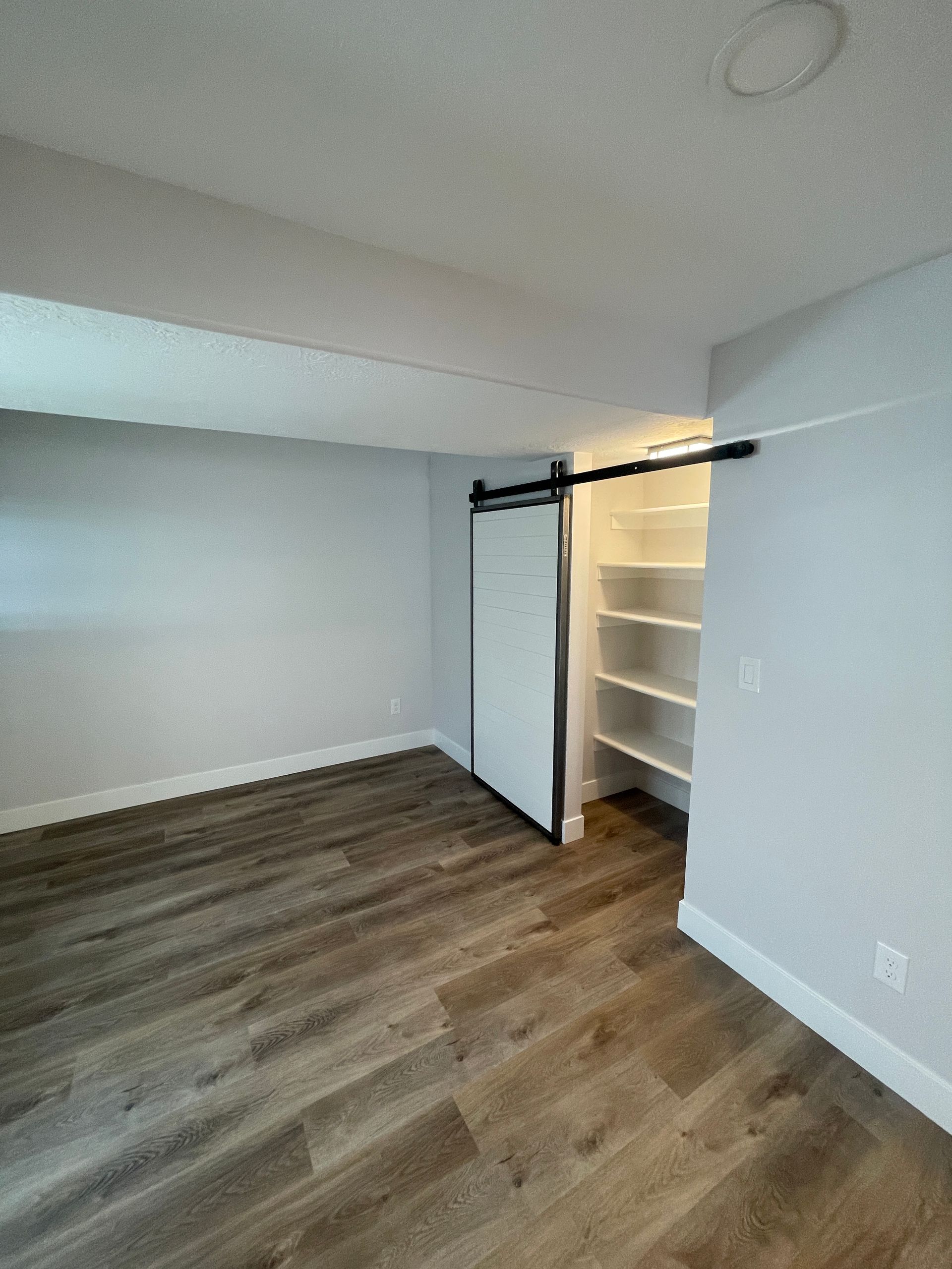 An empty room with a sliding barn door and shelves.