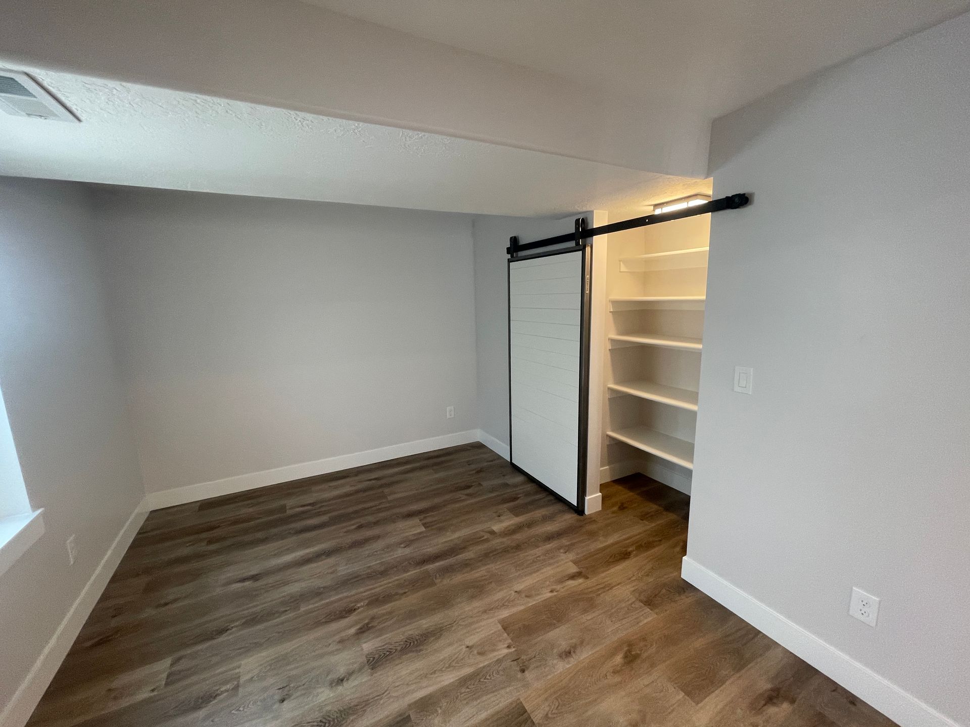 An empty room with a sliding barn door and shelves.