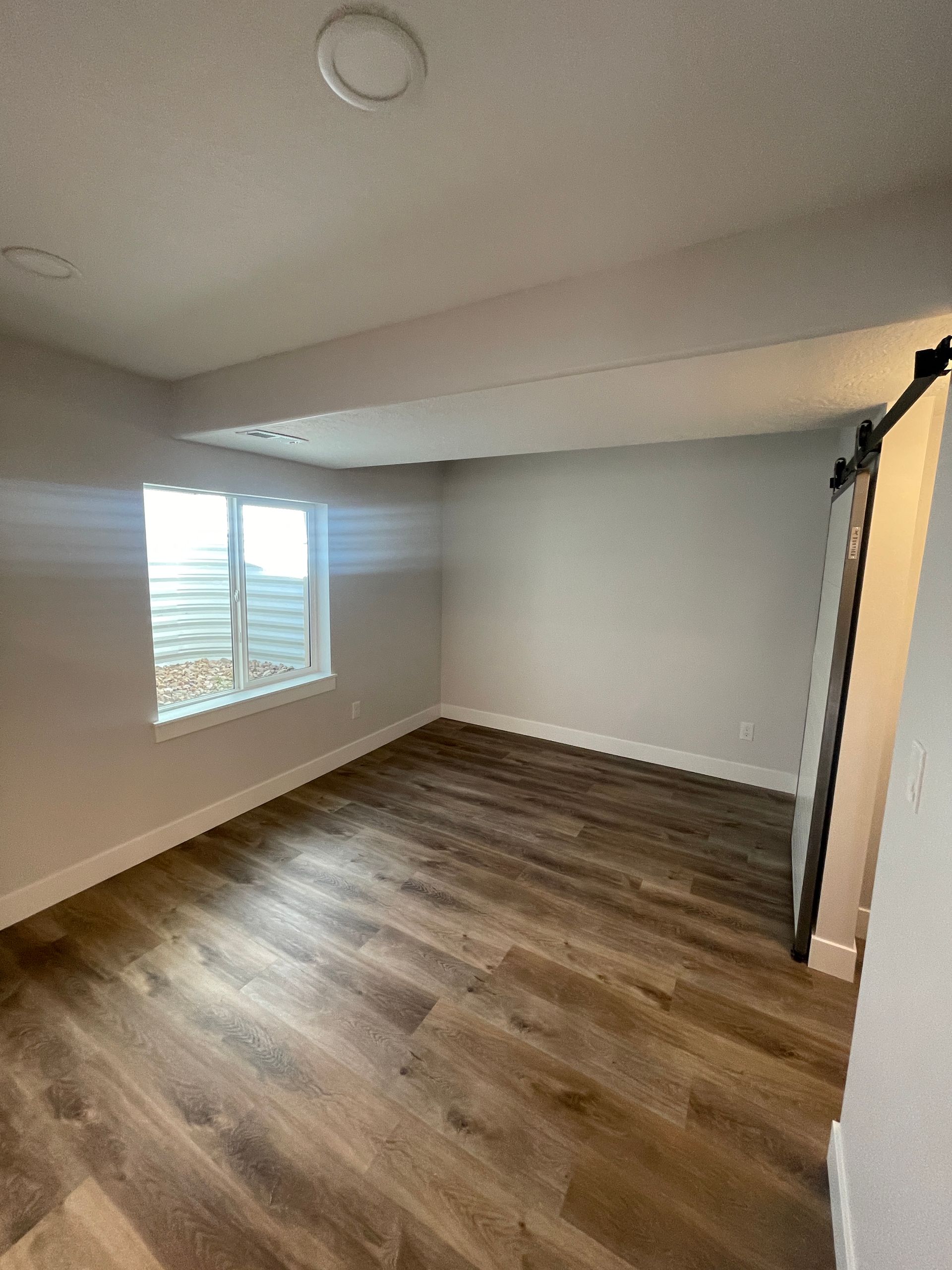 An empty room with hardwood floors and a window.