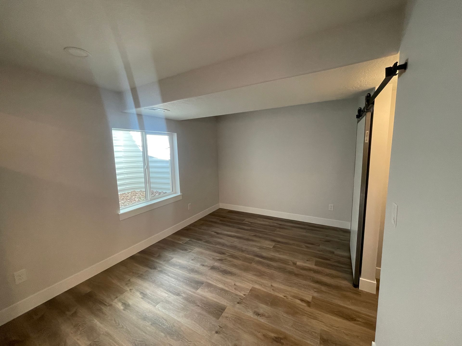 An empty room with hardwood floors and a window.