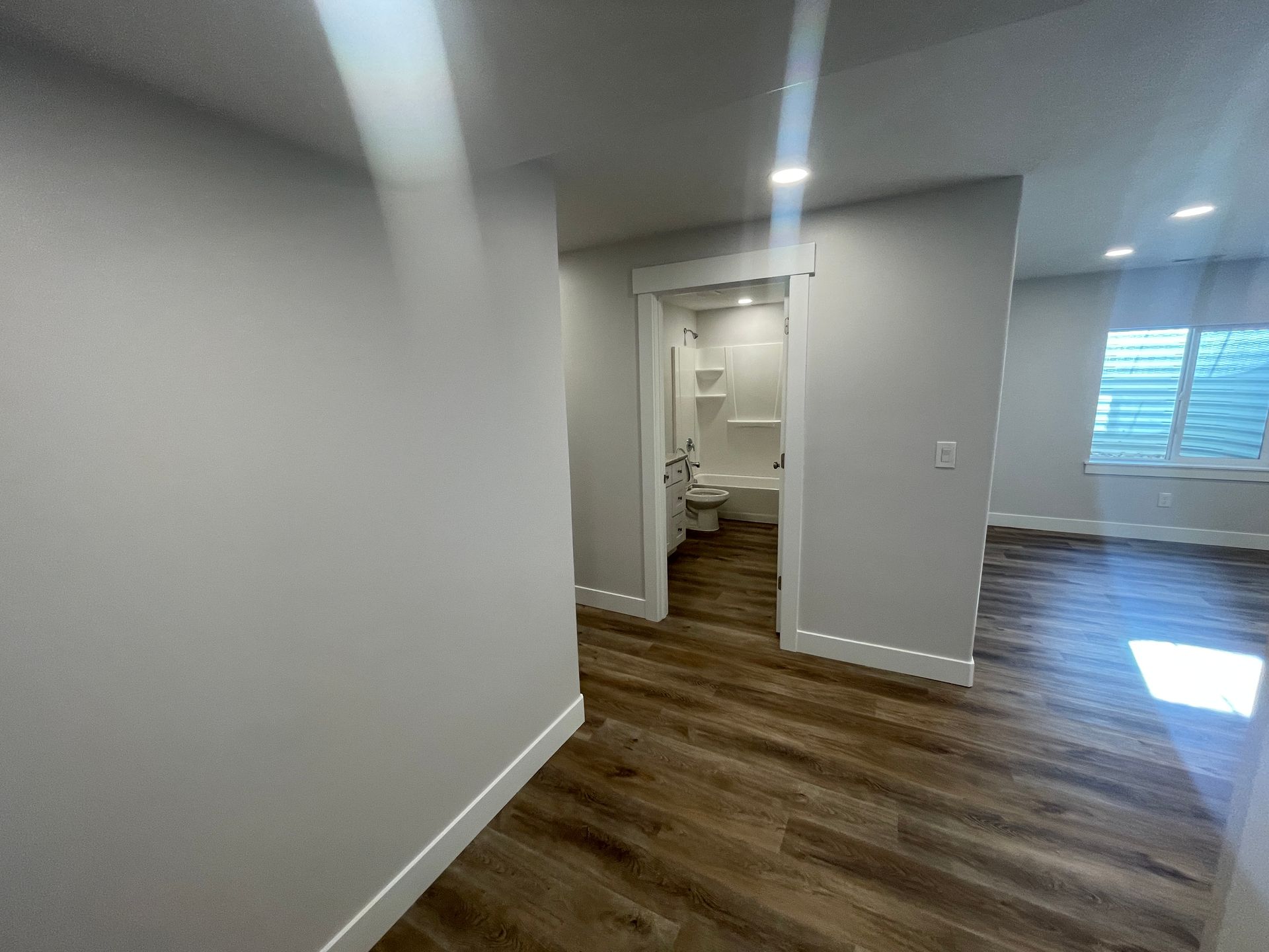 A hallway leading to a bathroom and a toilet in a house.