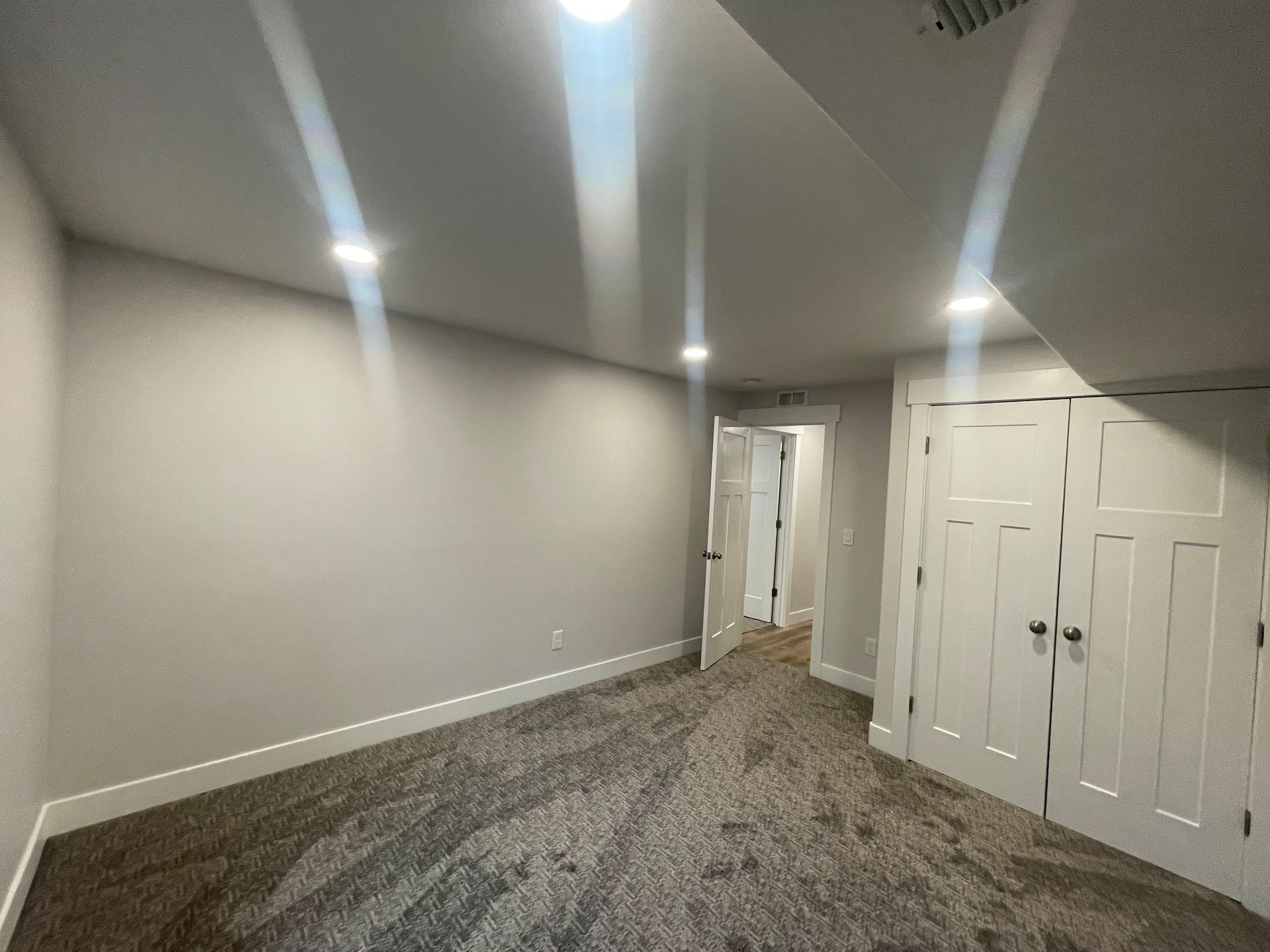 An empty room with a carpeted floor and white walls.
