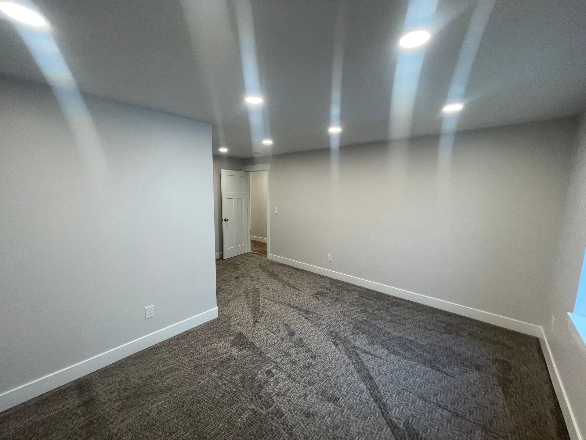 An empty room with a carpeted floor and white walls.