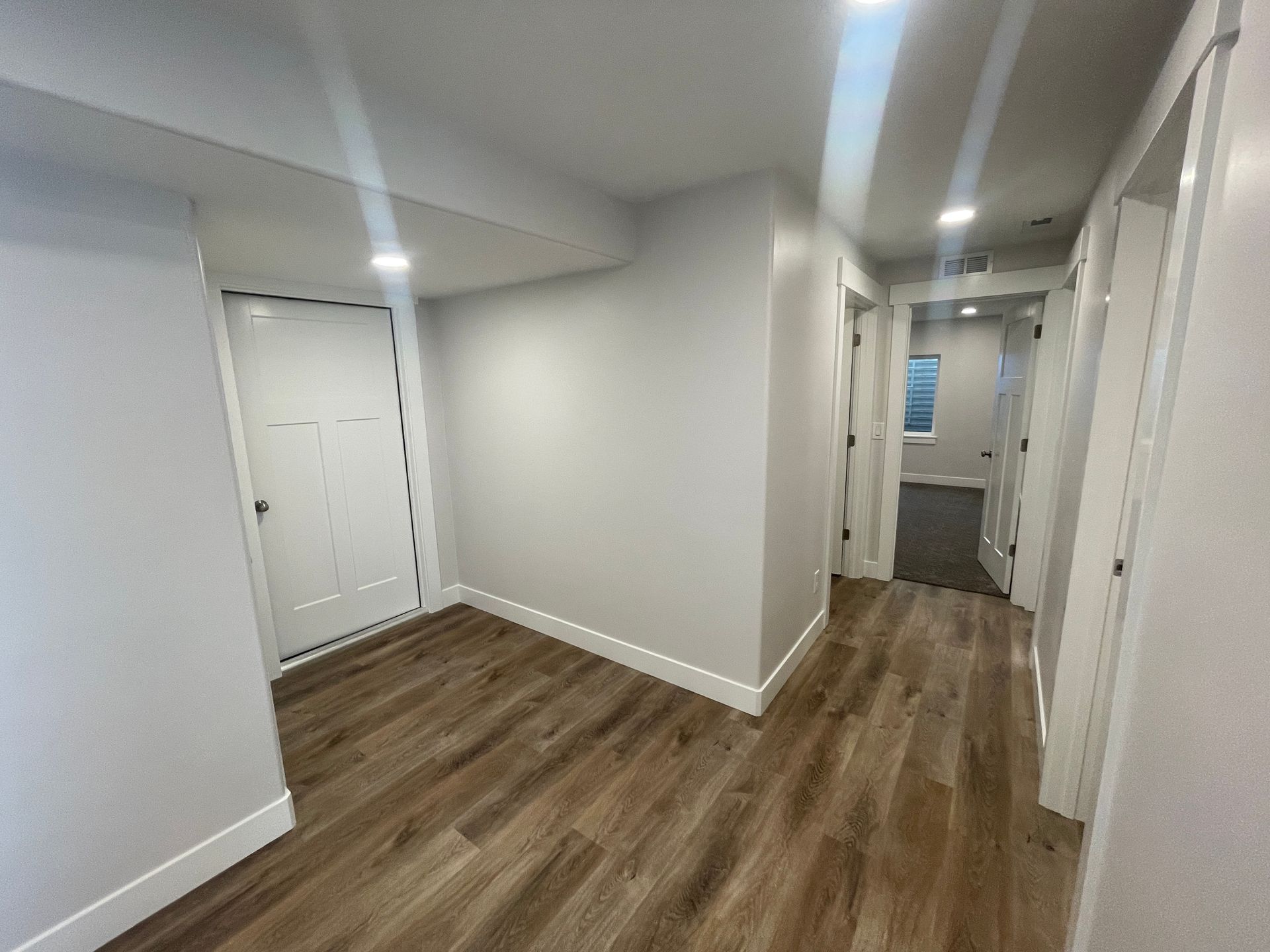 A hallway in a house with hardwood floors and white walls.