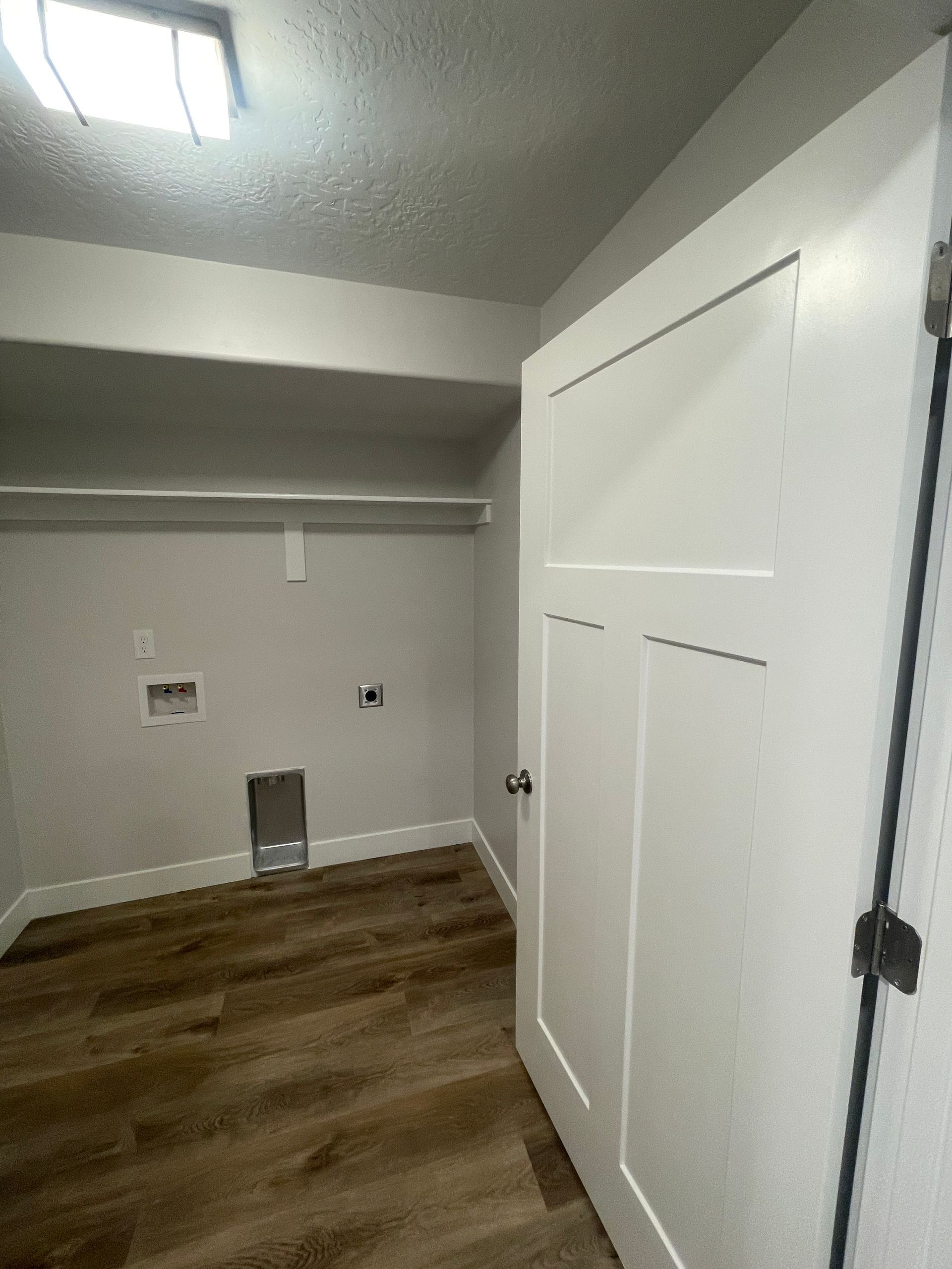 A laundry room with a wooden floor and white doors.