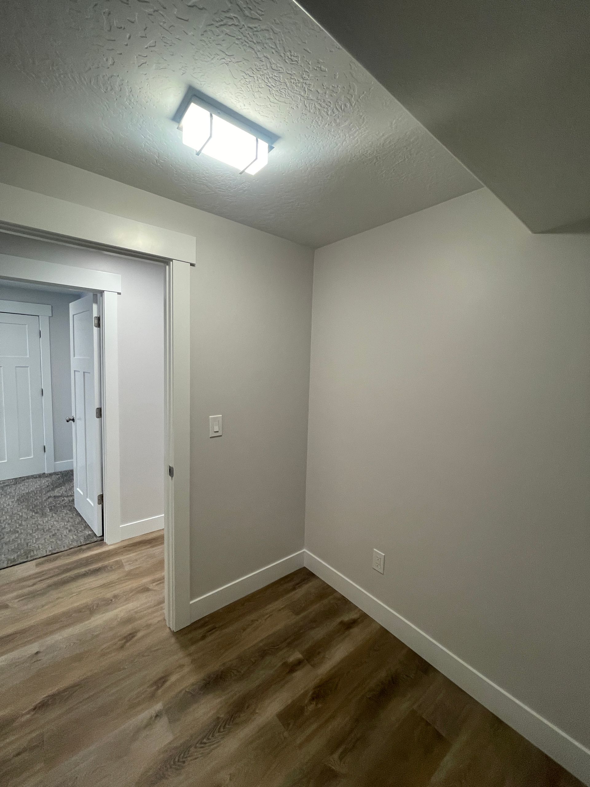 An empty room with hardwood floors and a light on the ceiling.