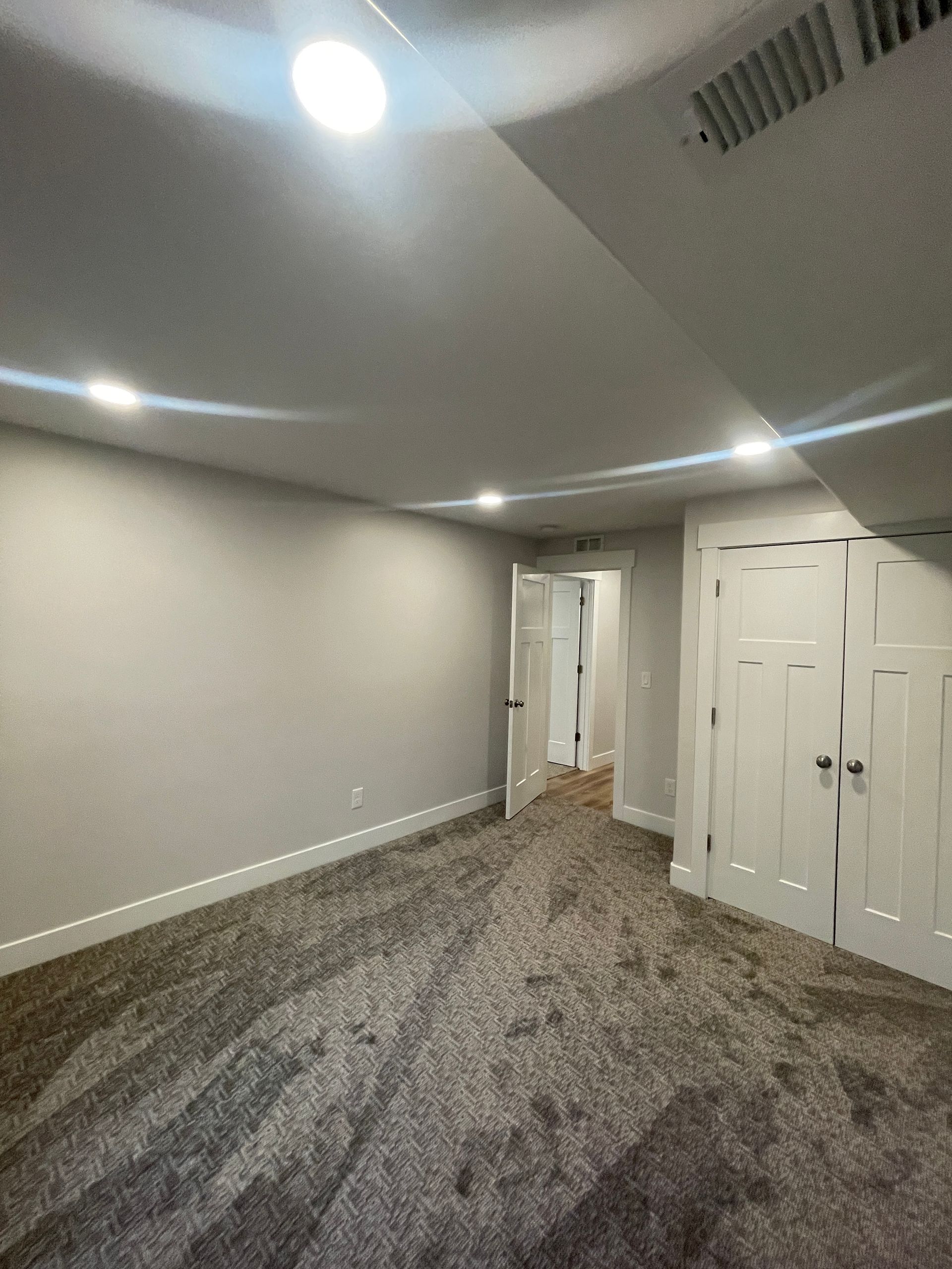 An empty basement with a carpeted floor and white walls.