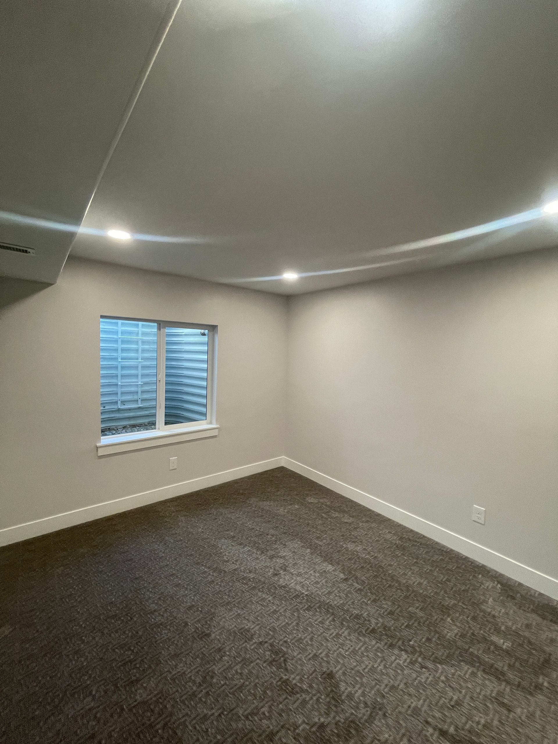 An empty room with a window and a carpeted floor.