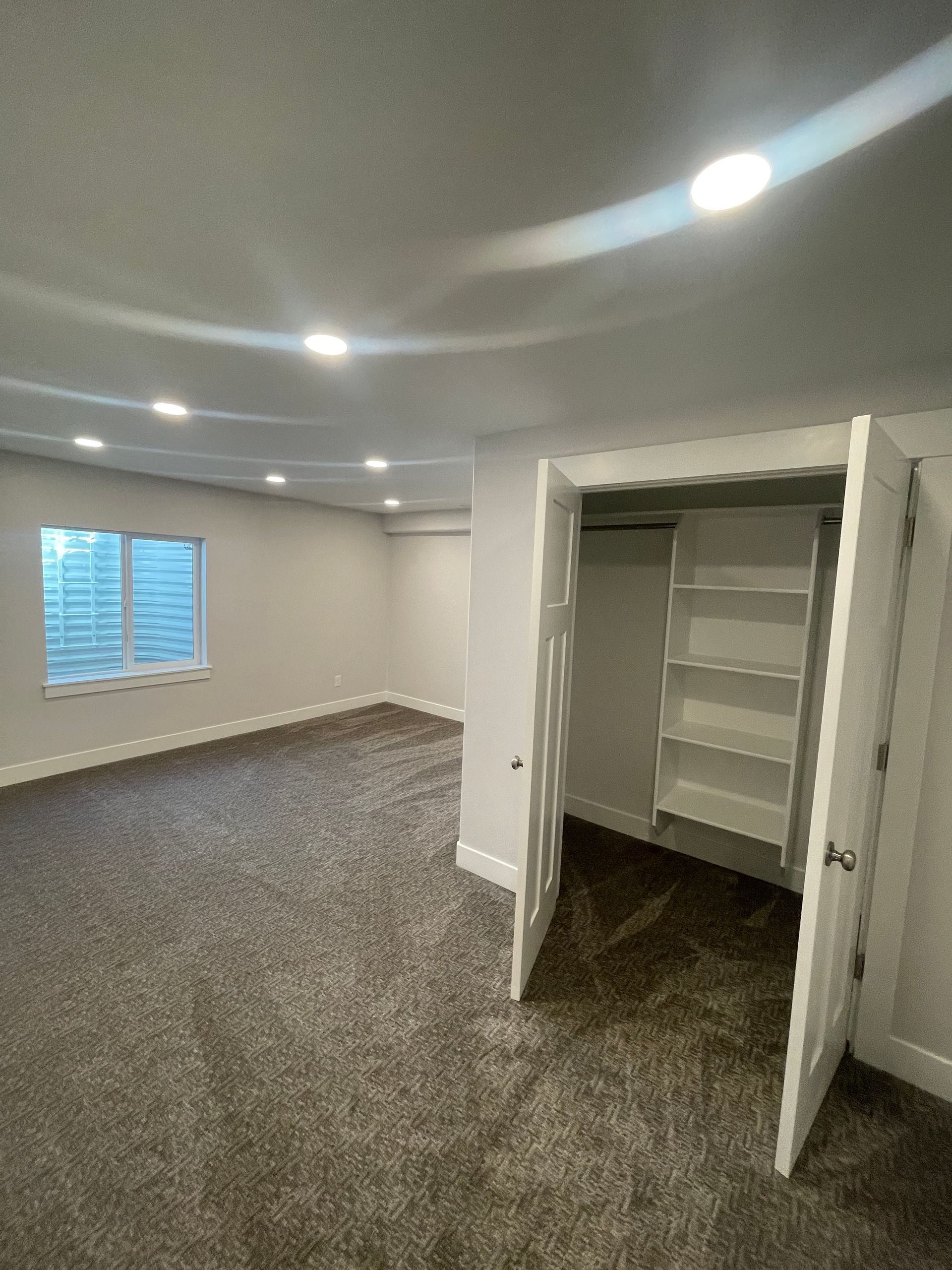 An empty room with a closet and a window.