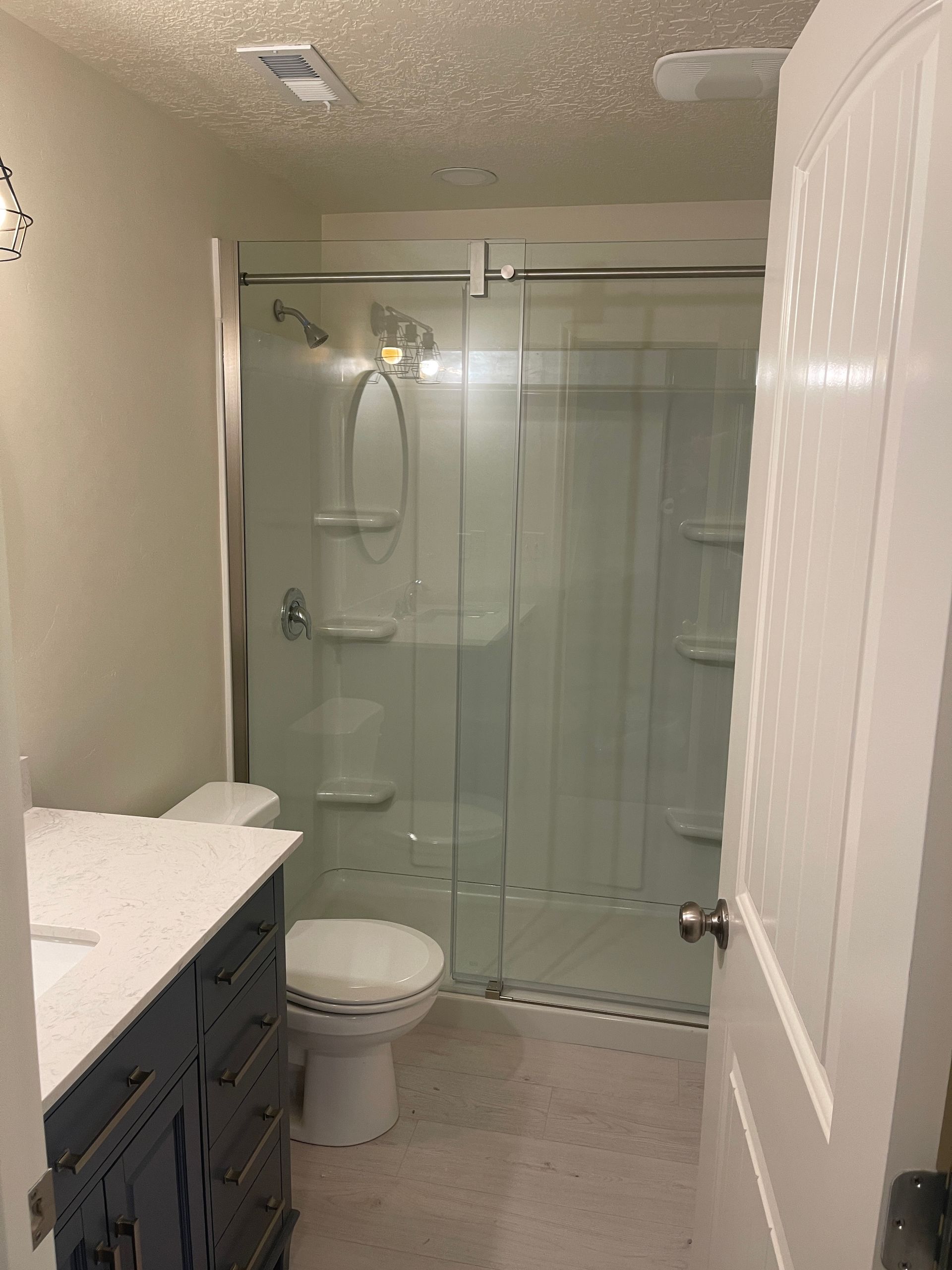 A bathroom with a toilet , sink and shower.