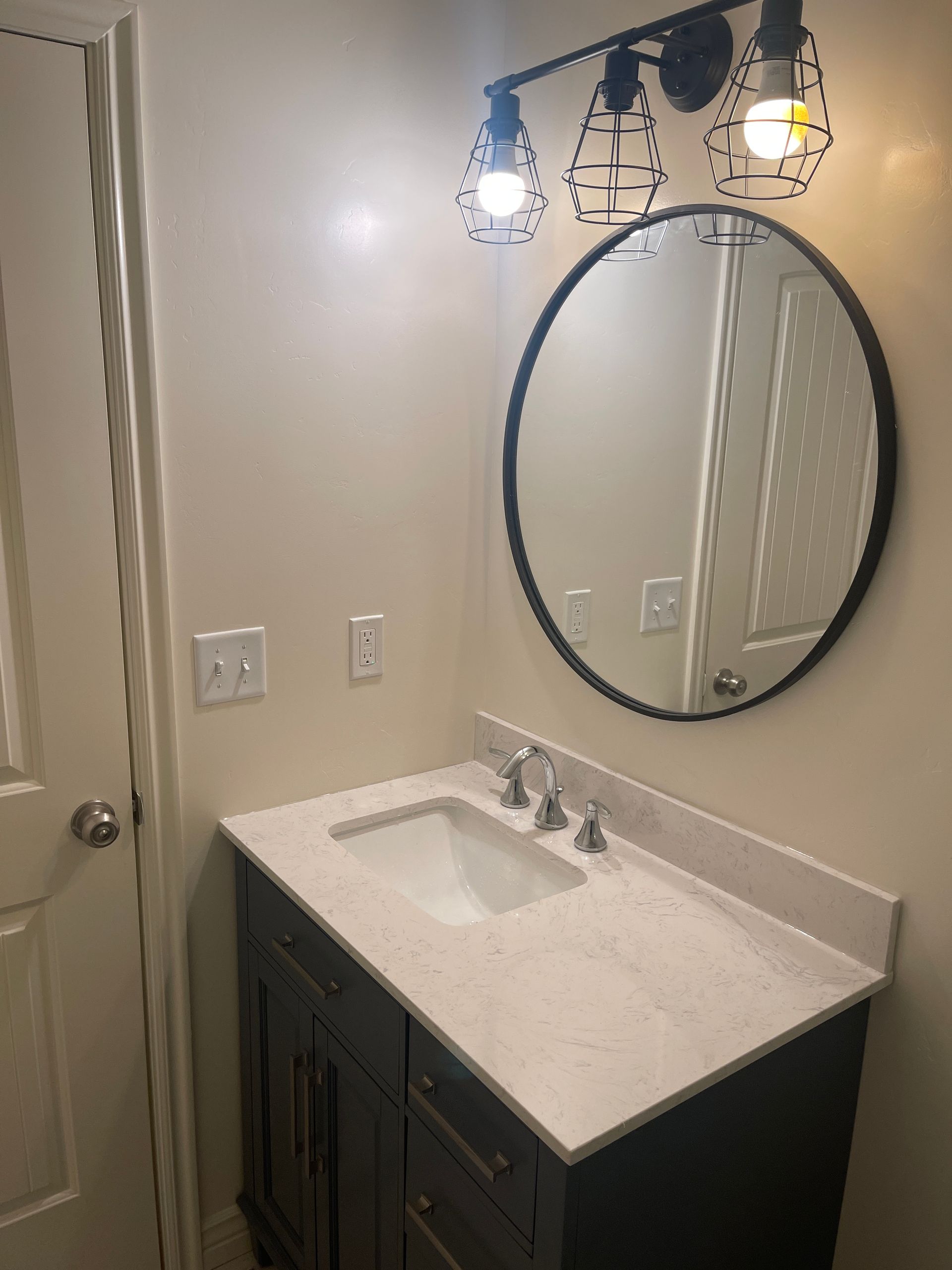 A bathroom with a sink and a round mirror