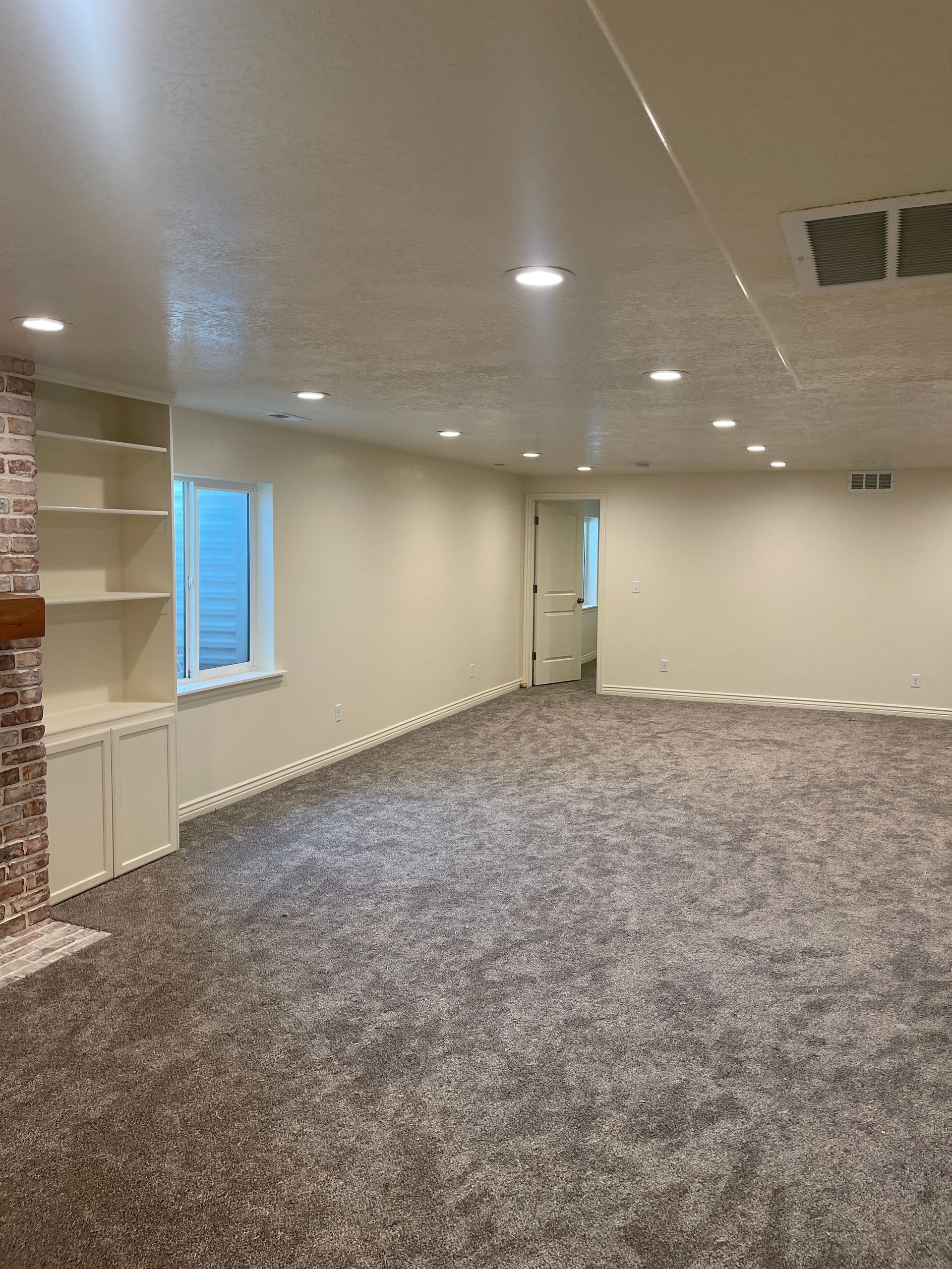 A large empty room with a carpeted floor and a fireplace.