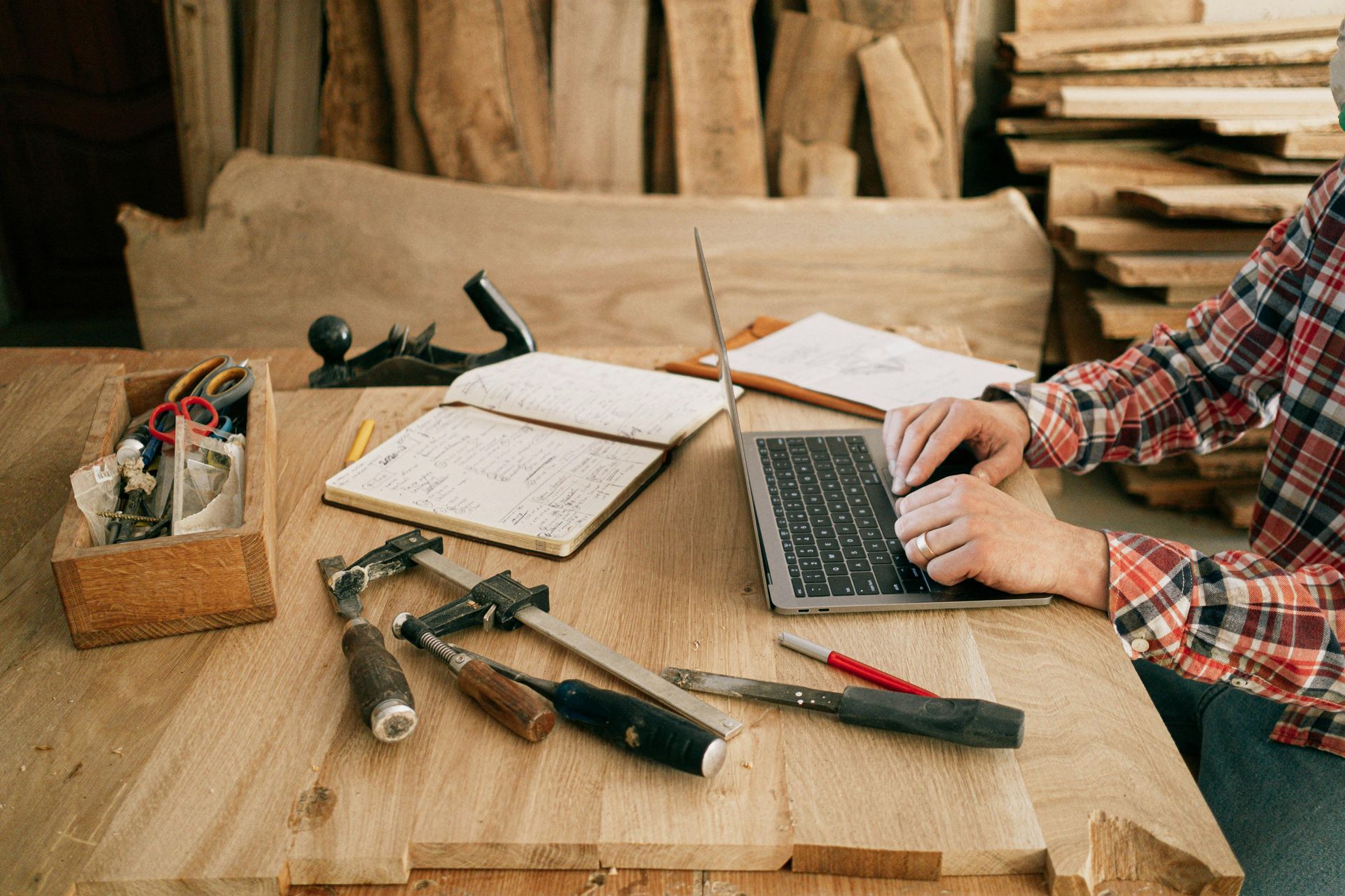 man working on laptop surrounded by hand tools