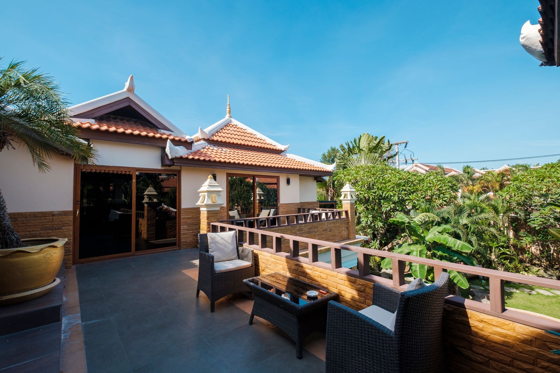 A balcony with chairs and a table in front of a house.
