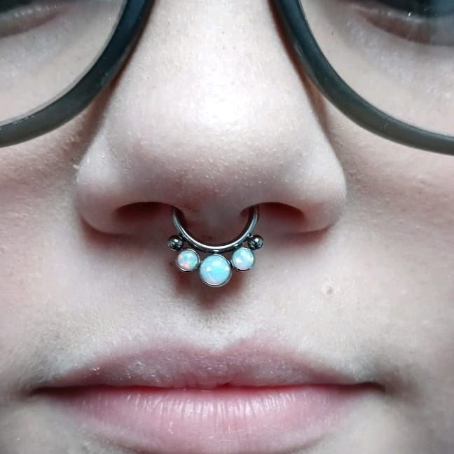 a close up of a woman 's nose with a nose ring and glasses .