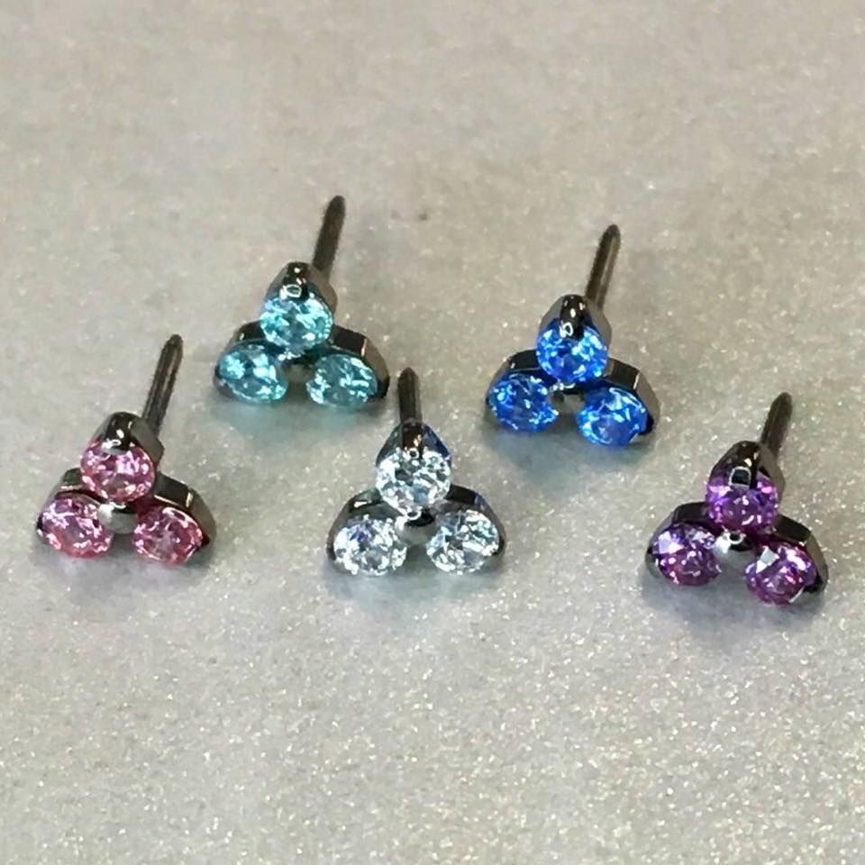 three pairs of earrings are sitting on a white surface .