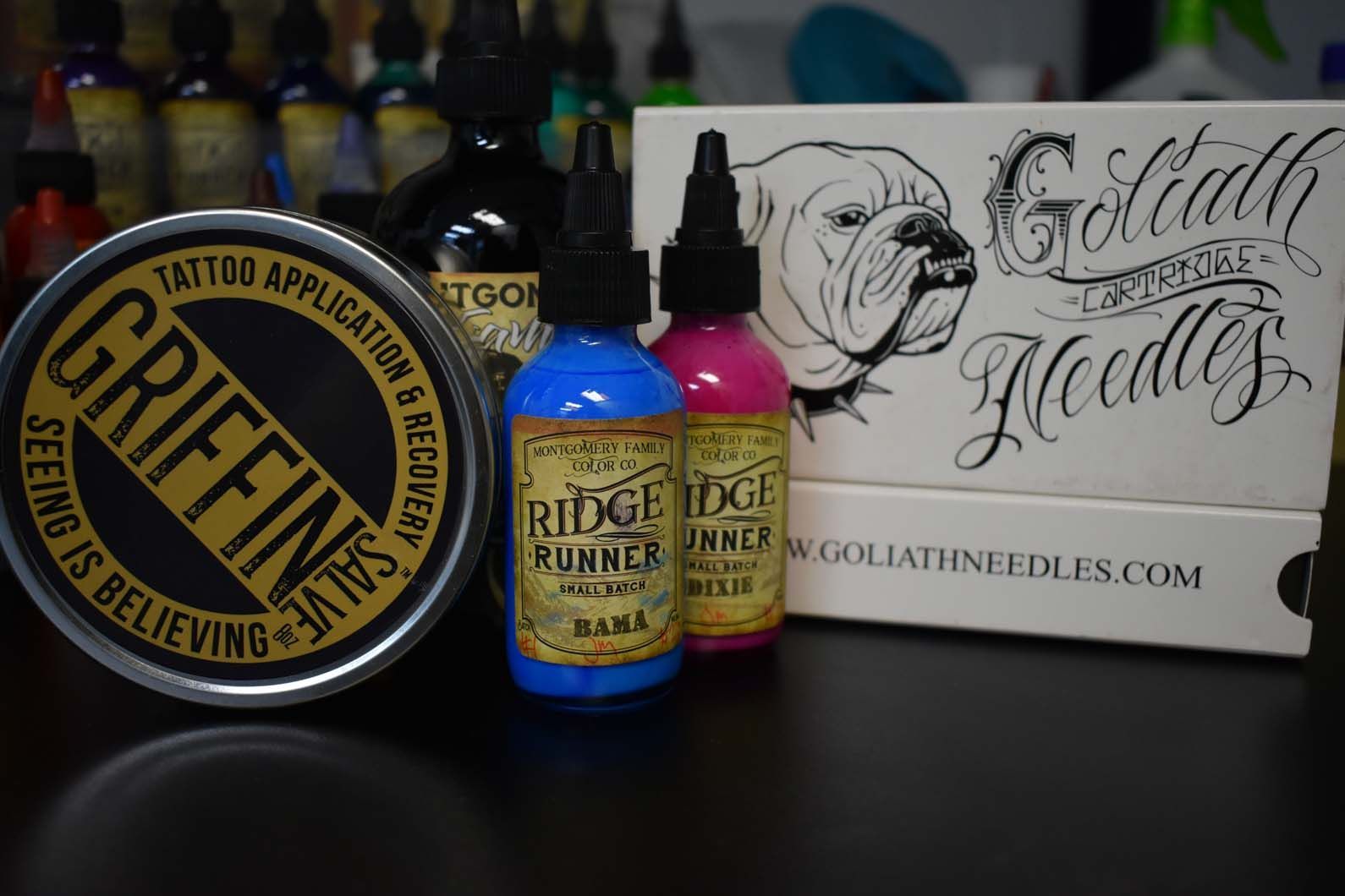 a bottle of griffin salve is sitting on a table next to bottles of tattoo ink 