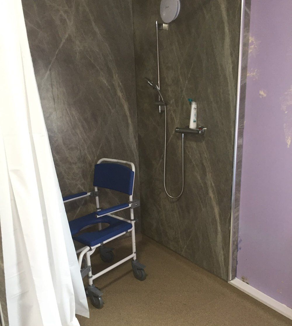 Wet room with white shower curtain and shower chair