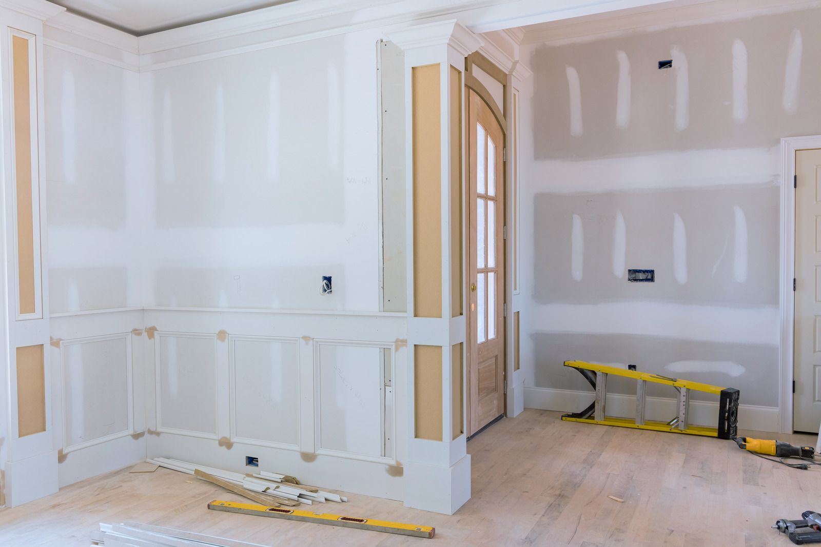 A room in a house under construction with drywall and a ladder.