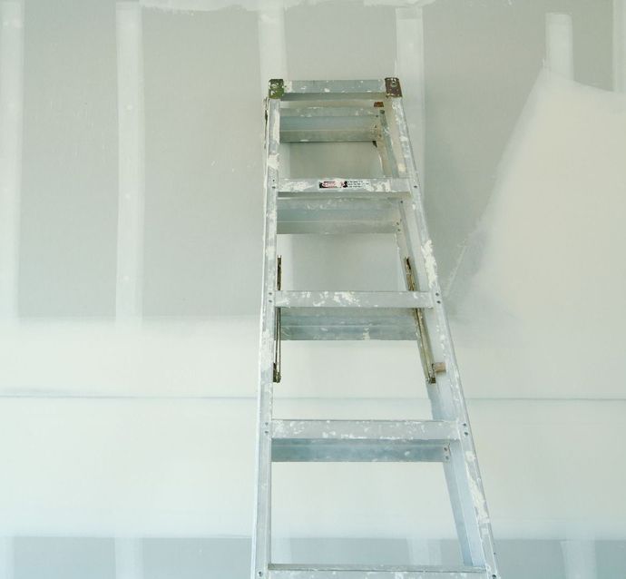 A ladder is leaning against a white wall.