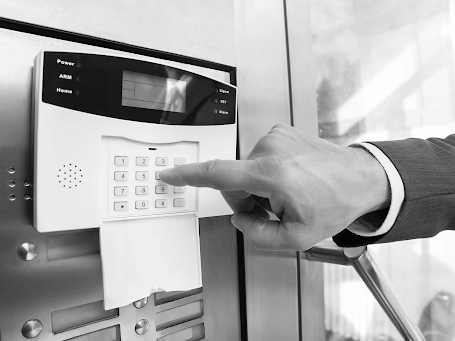 Hand pressing a keypad on a wall-mounted security or intercom system