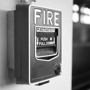 Wall-mounted fire alarm pull station with black cover and white