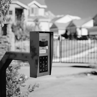 Black-and-white doorbell intercom on a fence in a suburban neighborhood