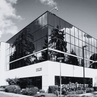Modern glass office building with reflective windows and landscaping