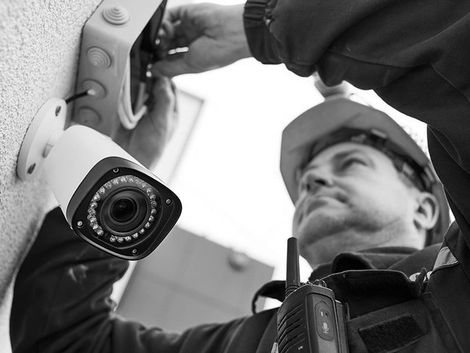 Security camera mounted on a pole while a worker in a hard hat adjusts it