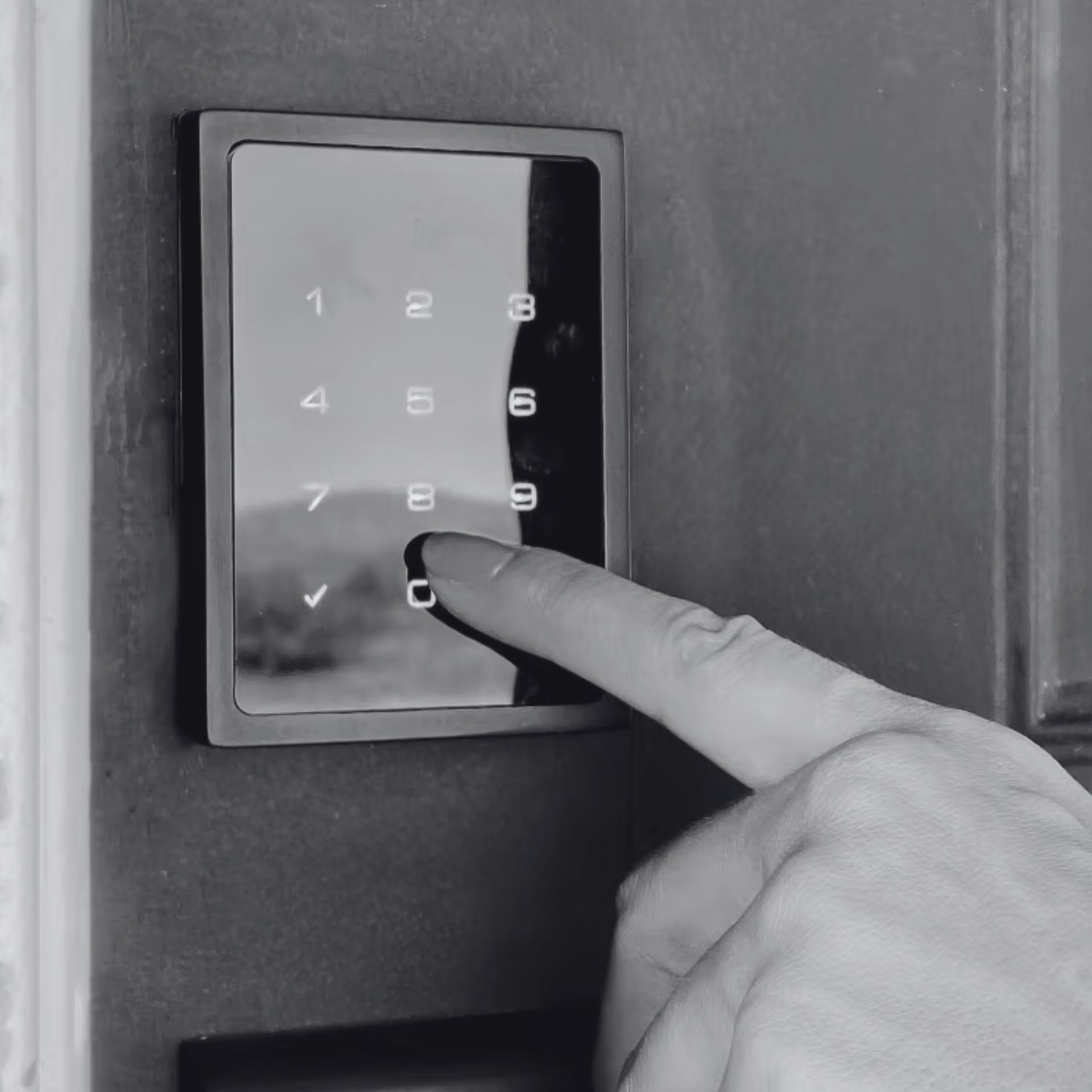 Finger pressing a lit numeric keypad on a wall-mounted security panel