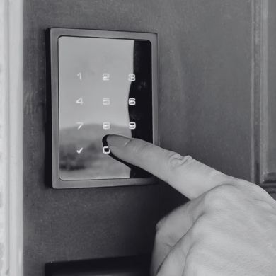 Finger pressing a lit numeric keypad on a wall-mounted security panel