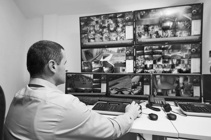 Man monitoring multiple CCTV screens at a security desk