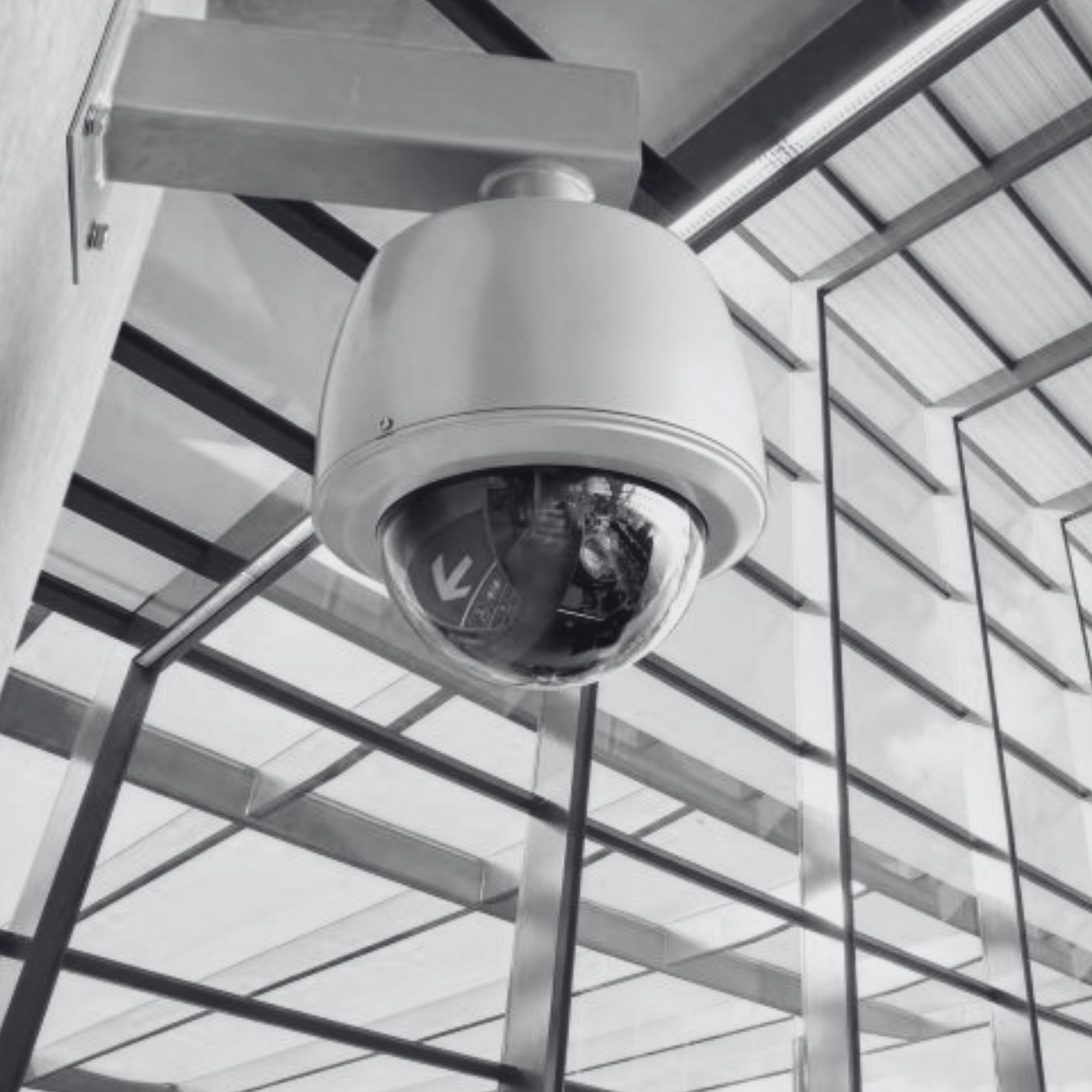 Security camera mounted on a ceiling in a glass-roofed building