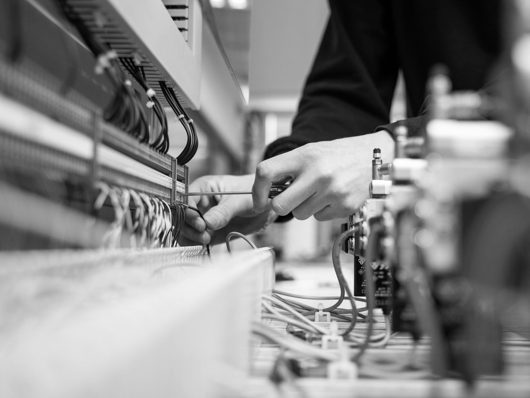 Technician adjusting cables in a server rack, with hands working among network wiring.