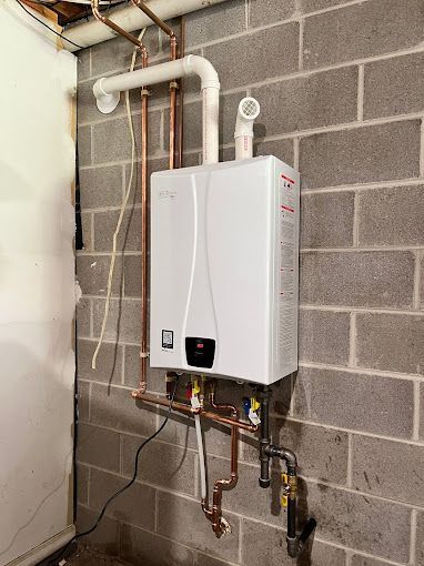 A white water heater is mounted to a brick wall.