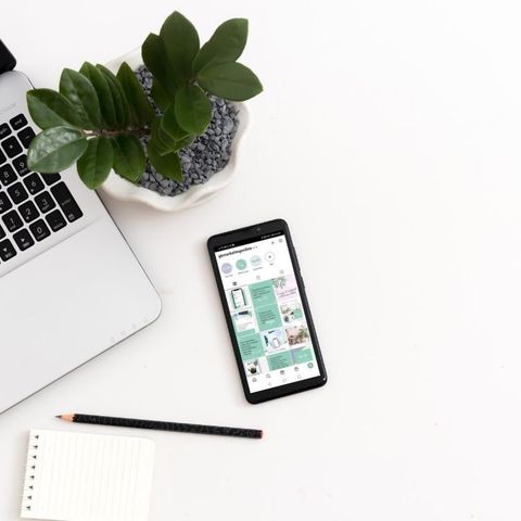 GK Marketing Online | A cell phone is sitting on a table next to a laptop and a potted plant.