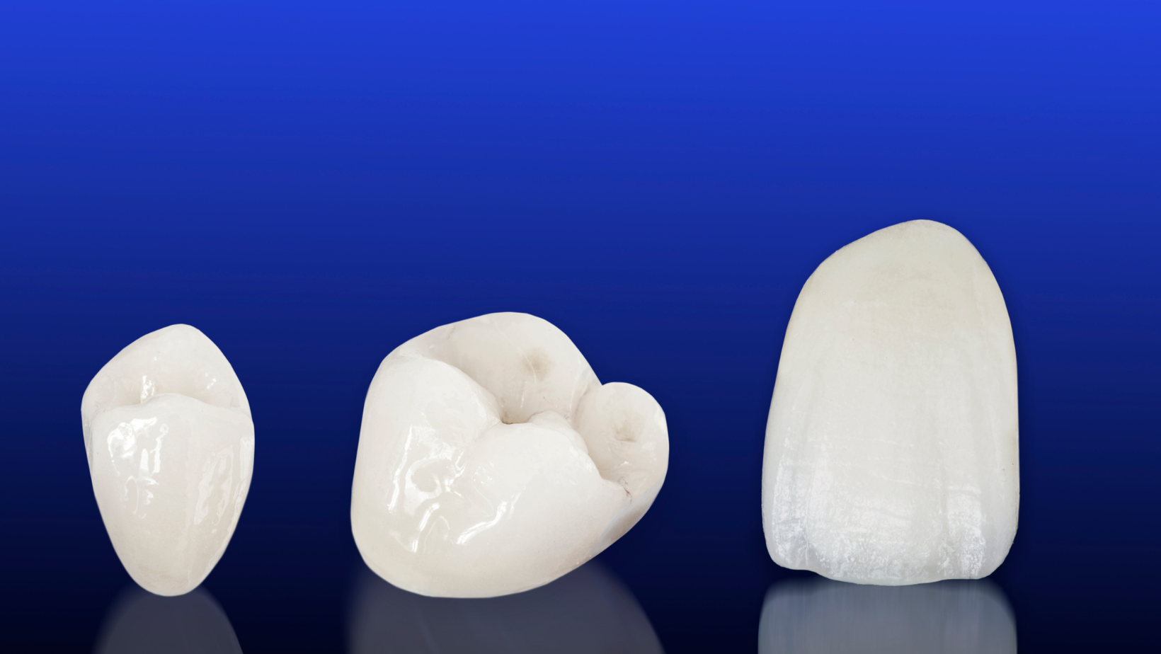 Three different types of dental crowns on a blue background