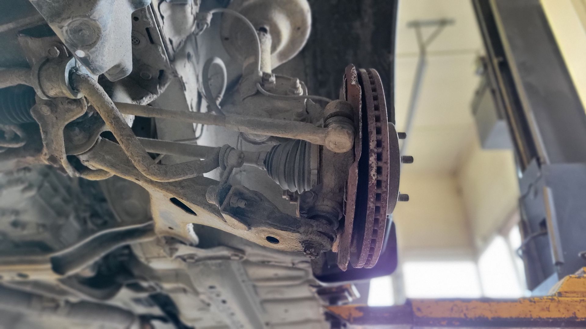 A close-up of a car on a hoist , showing a vehicle's suspension, including shocks and struts, in the lakeshore automotive shop in Kelowna.