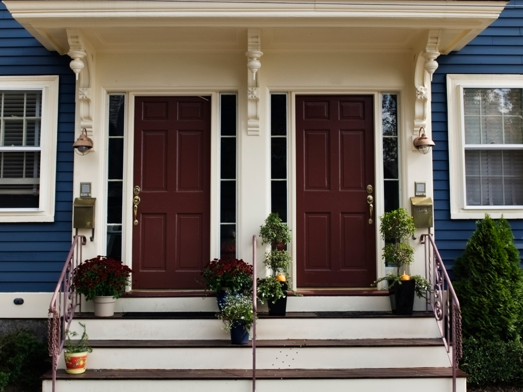 Two maroon front doors of a blue house, with matching white trim and small front steps.