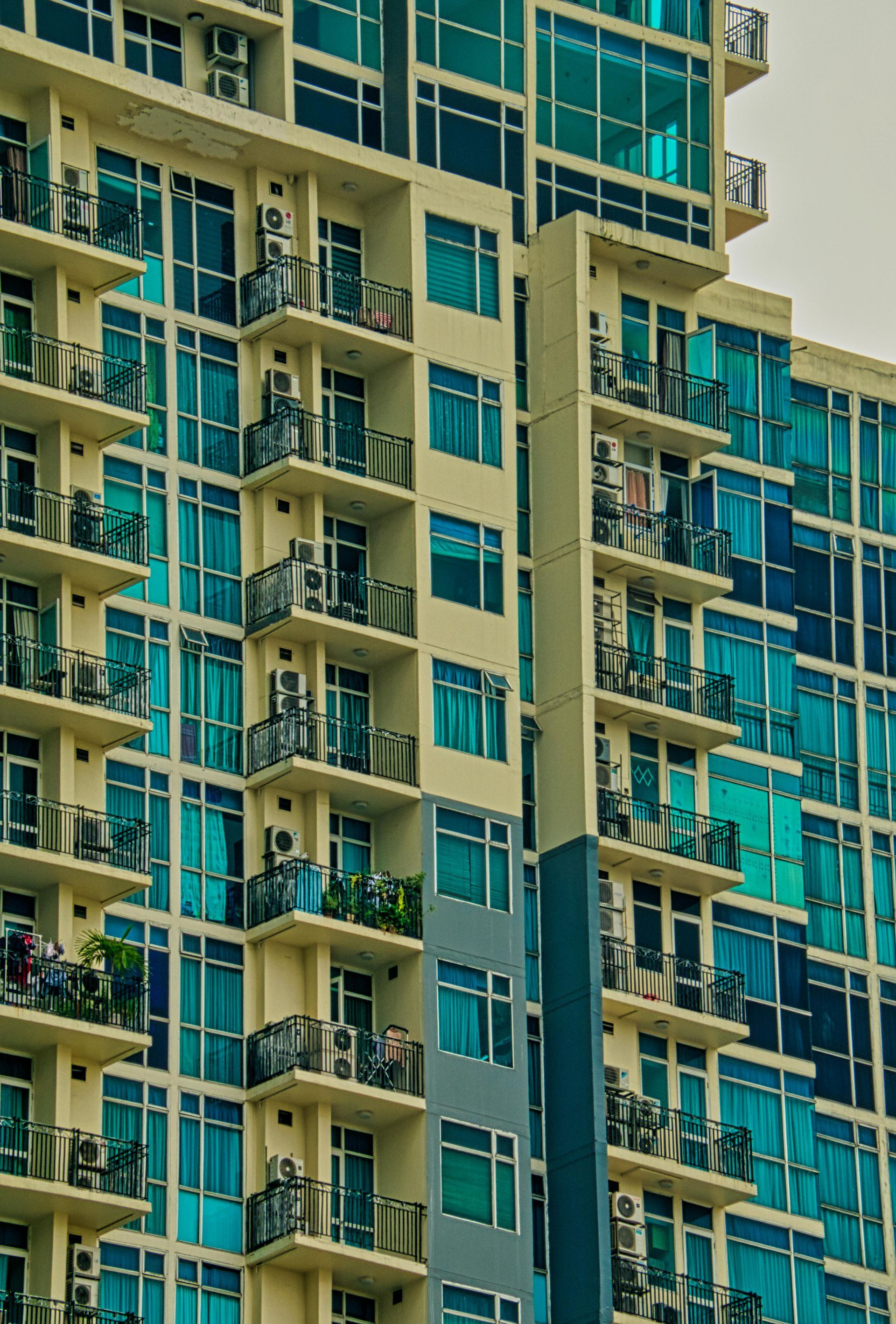 Multi-story apartment building with teal tinted windows and balconies.