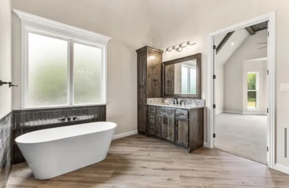 Bright modern bathroom with freestanding tub, double vanity, and frosted windows