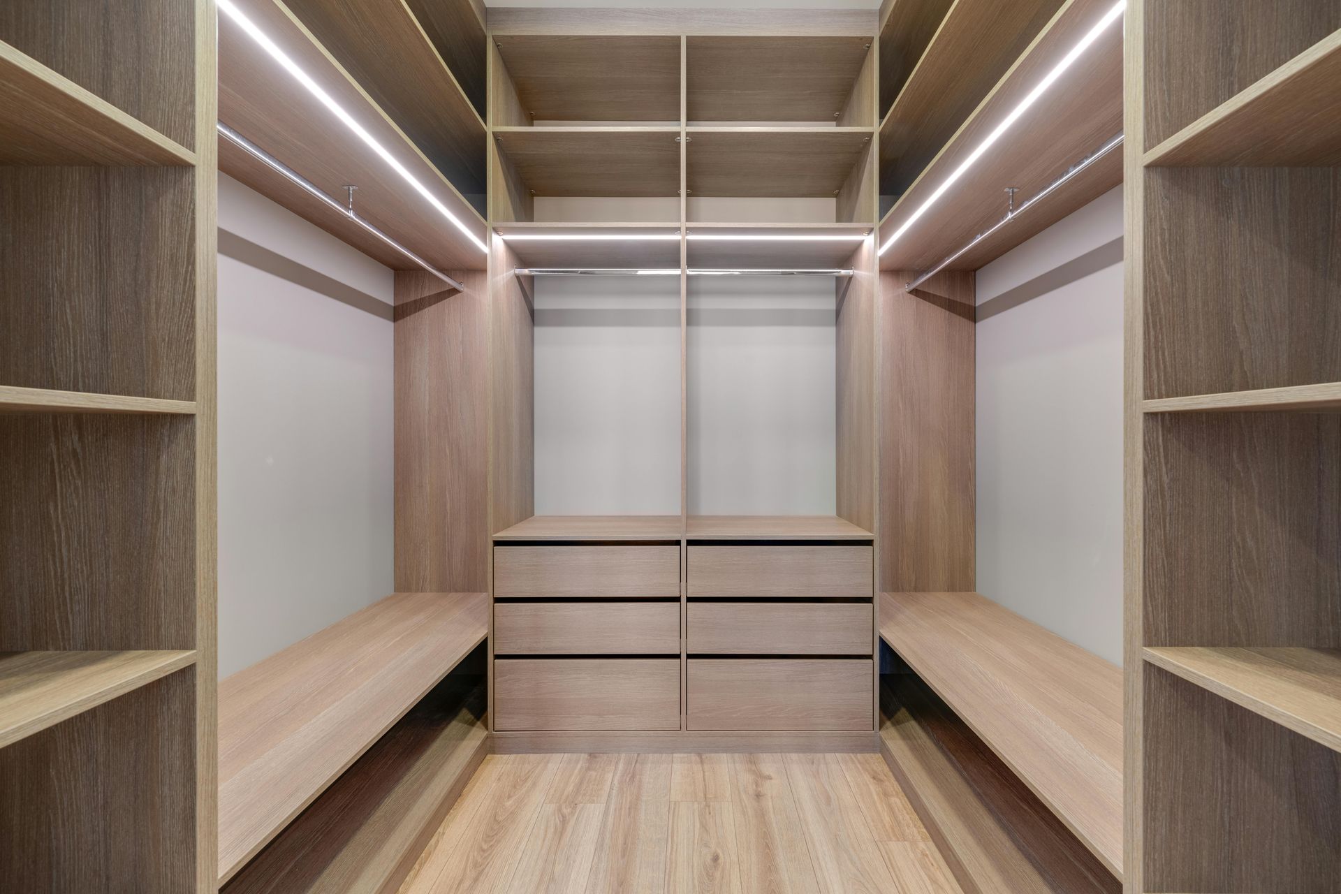Walk-in closet with wood shelving, hanging rods, drawers, and LED lighting on both sides